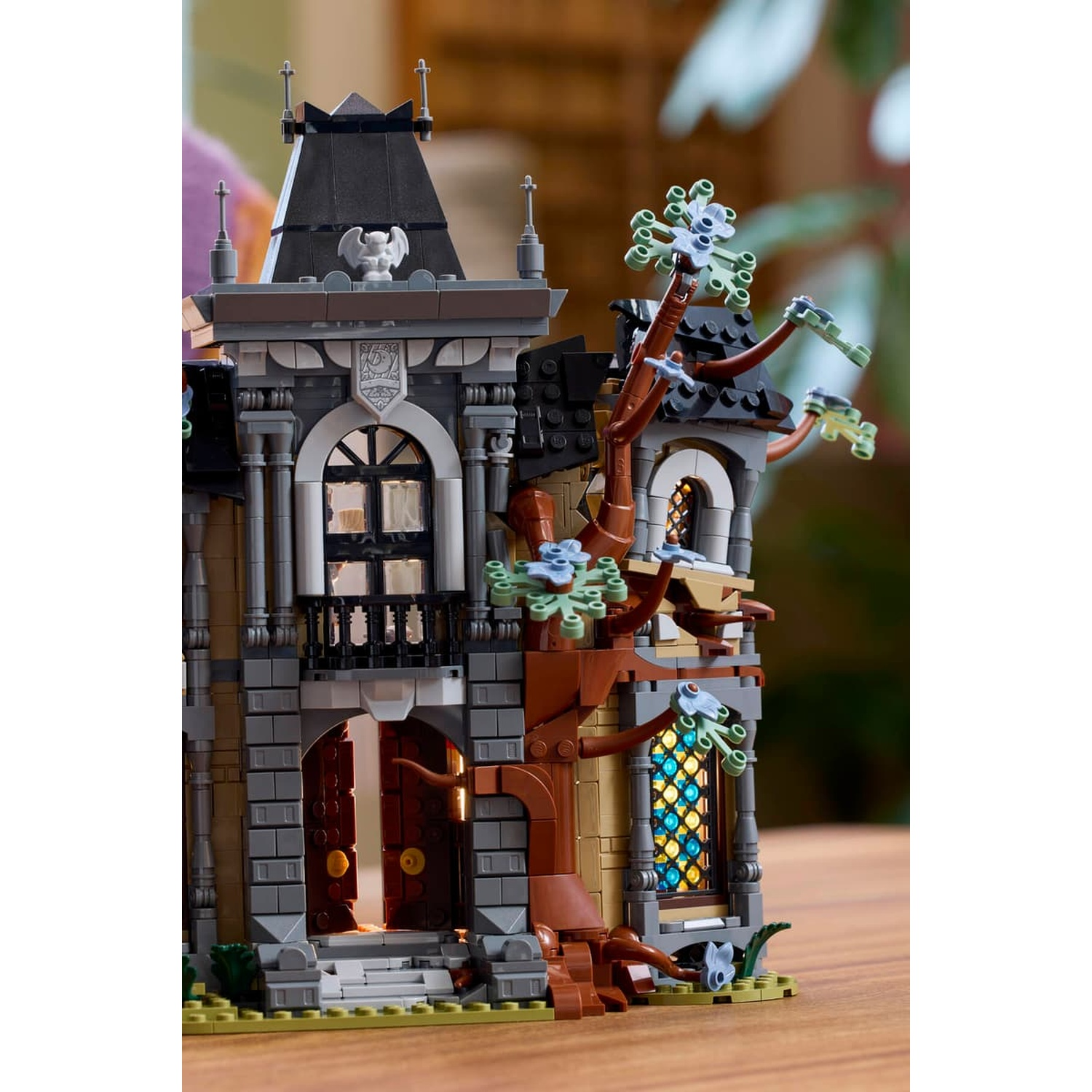 A detailed LEGO haunted house with a brown tree, glowing windows, and an open front door.