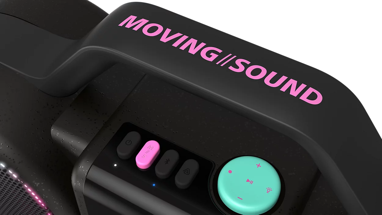 Fekete hangszóró rózsaszín MOVING SOUND felirattal, gombokkal és türkiz vezérlőtárcsával.