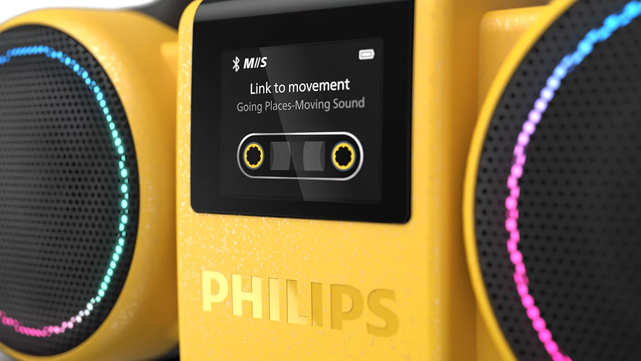 Közeli kép egy sárga Philips boomboxról megvilágított hangszórókkal és kazetta grafikát mutató digitális képernyővel.