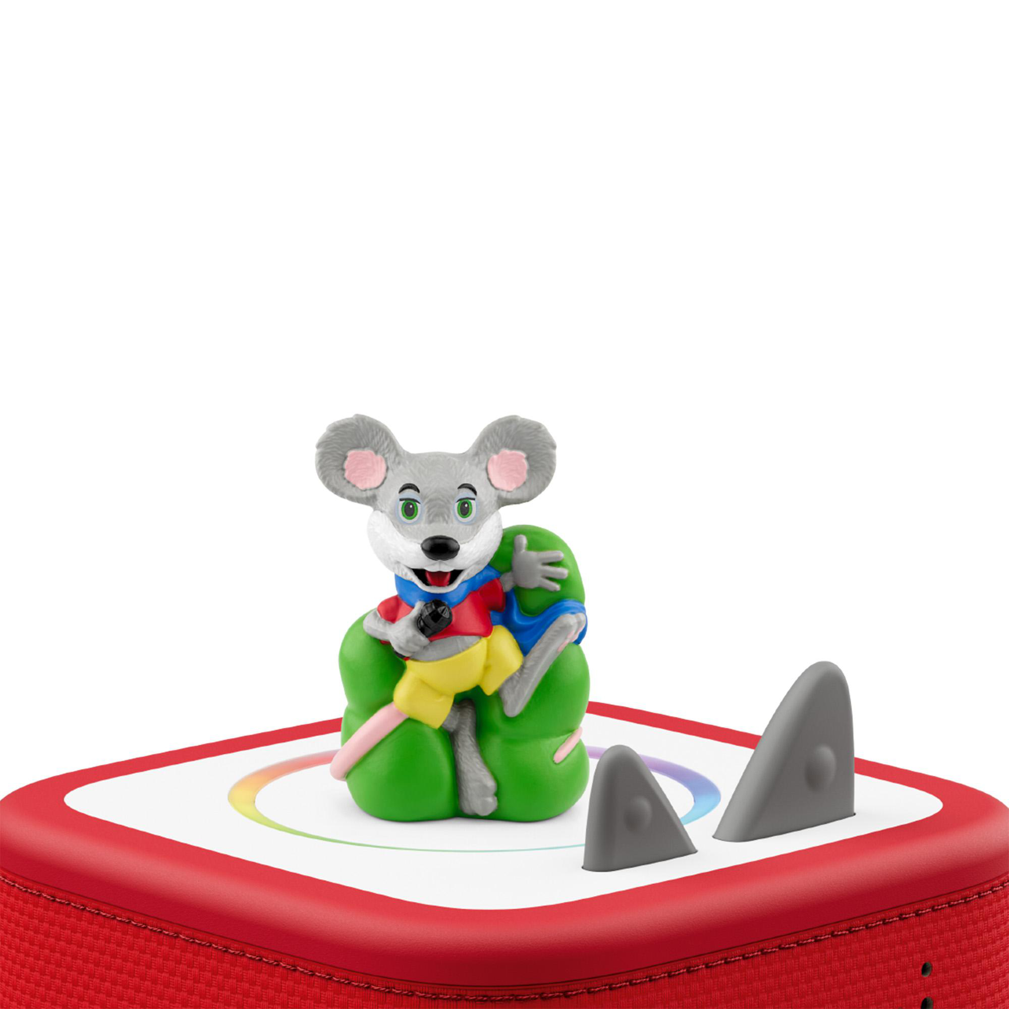 Eine graue Mausfigur mit rotem Oberteil und gelben Hosen sitzt auf grünem Kissen auf einem roten Lautsprecher.