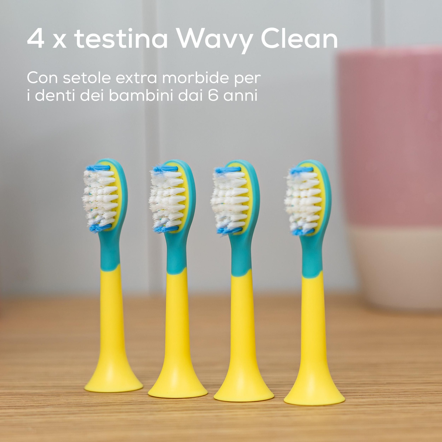 Quattro testine per spazzolino elettrico per bambini gialle e turchesi su una superficie in legno.