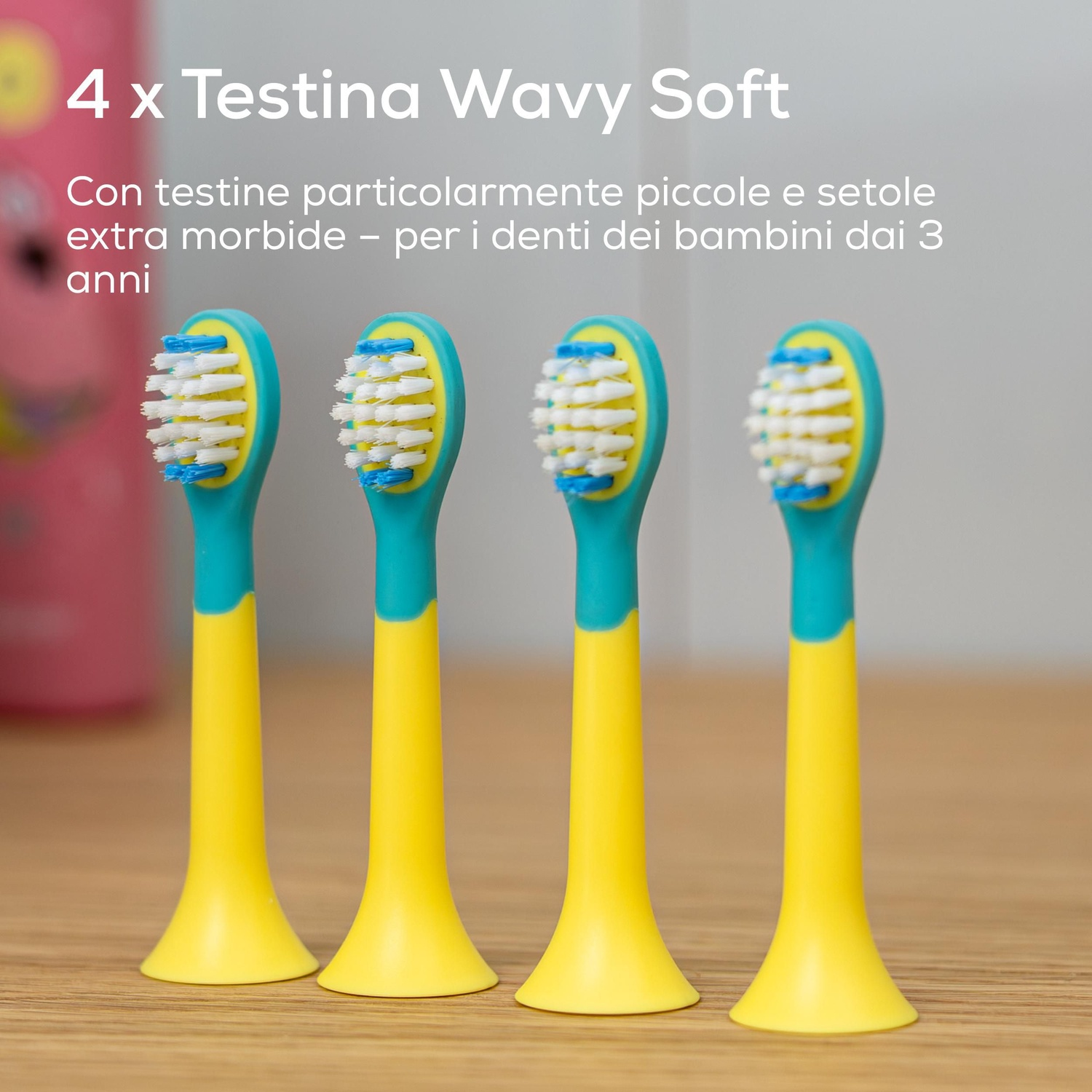 Quattro testine di ricambio per spazzolini da bambini allineate su una superficie di legno.