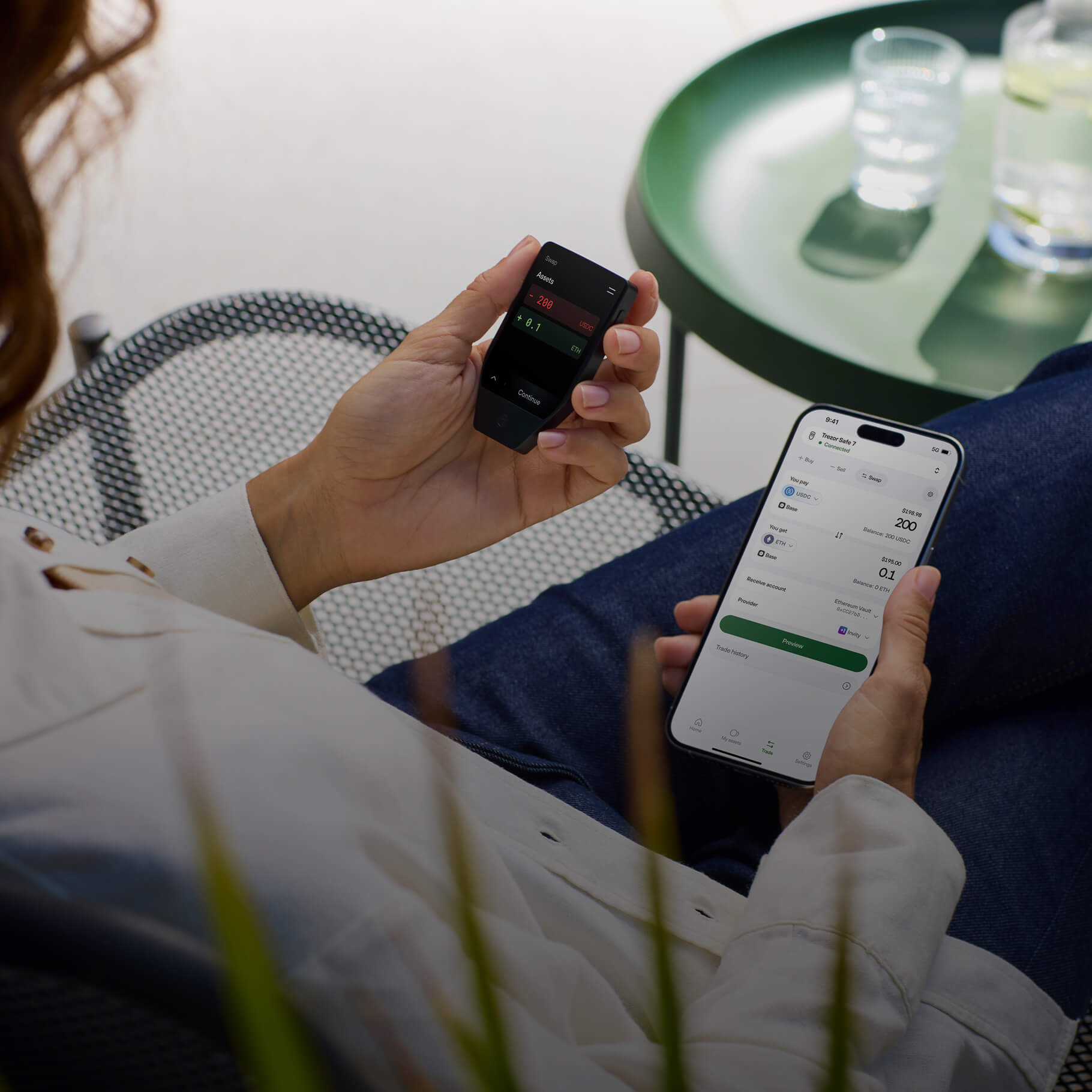 Person hält eine Krypto-Hardware-Wallet und ein Smartphone mit App.