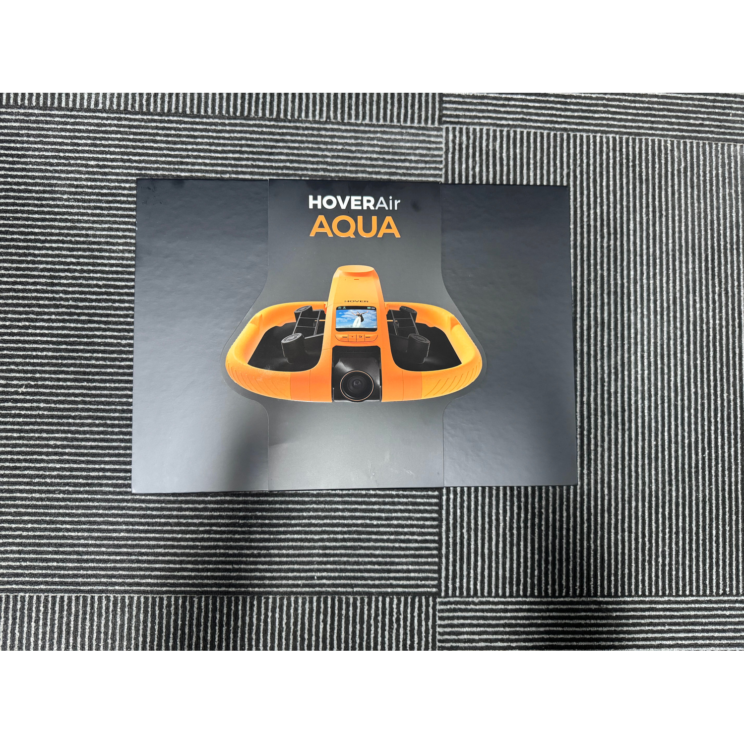 Scatola nera del dispositivo HoverAir Aqua su tappeto grigio.