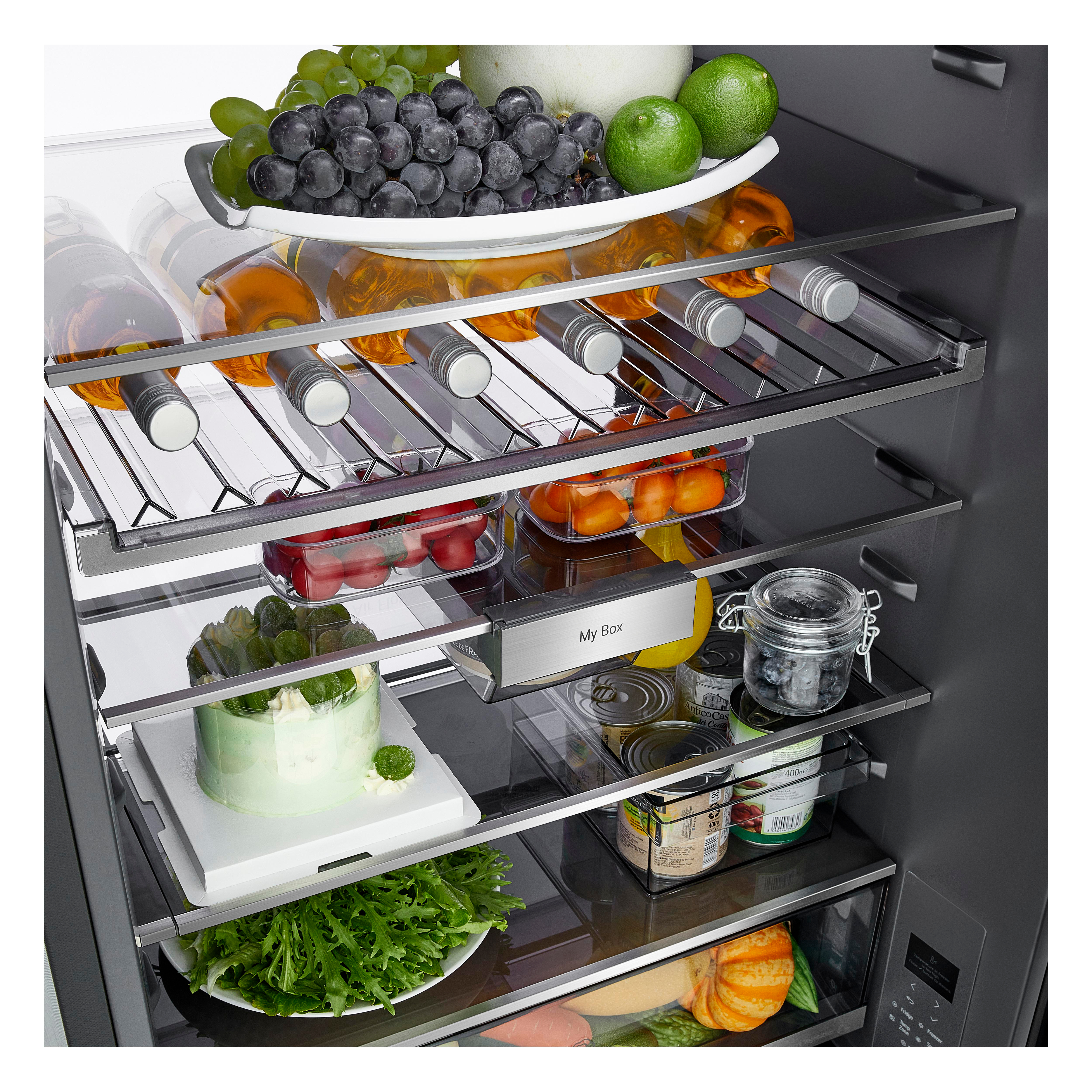 Ein vollgepackter Kühlschrank mit frischem Obst, Wein, Gemüse, einem grünen Kuchen und Dosen auf den Regalen.