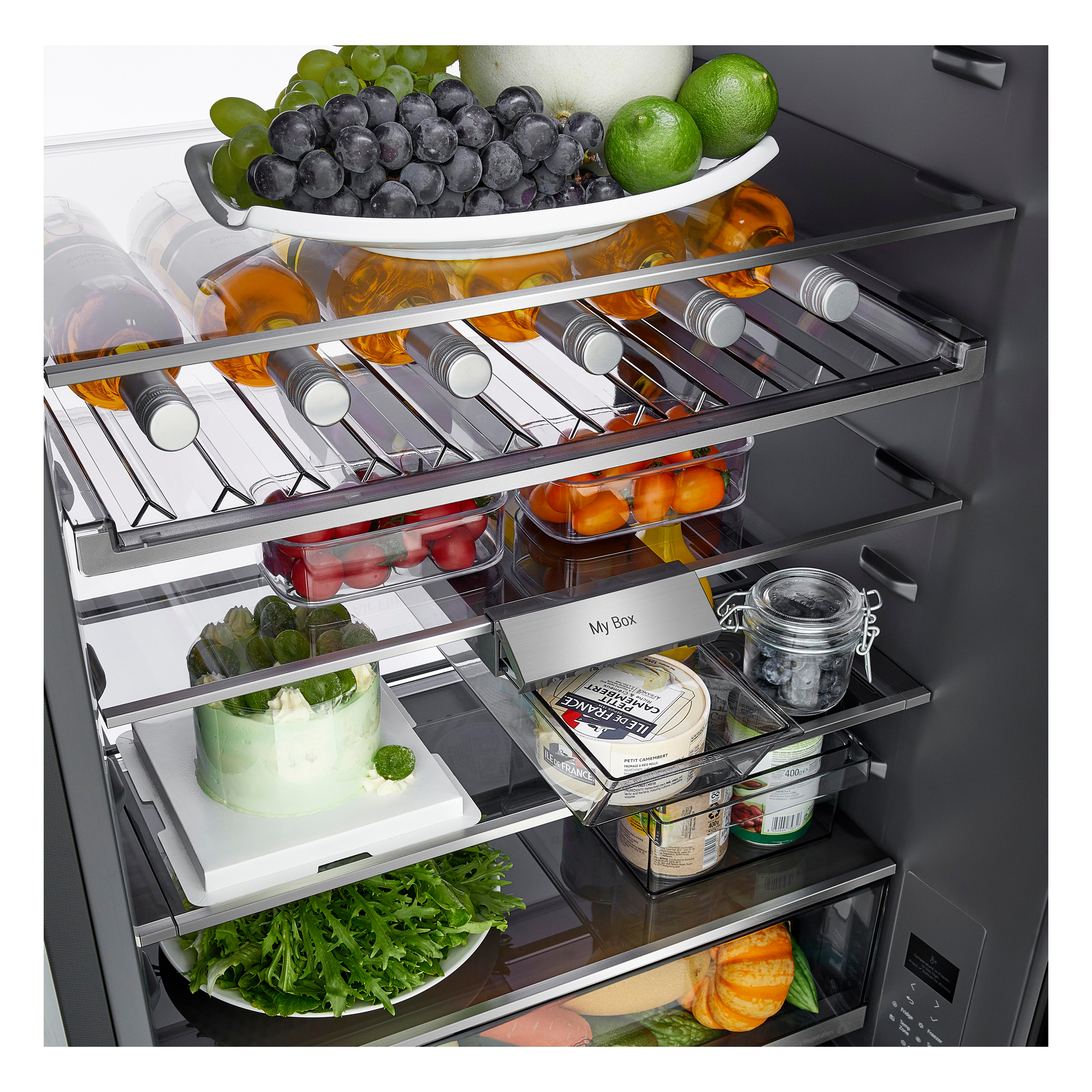 Ein gut gefüllter Kühlschrank mit frischem Obst, Wein, Gemüse und einem Kuchen auf den Regalen.