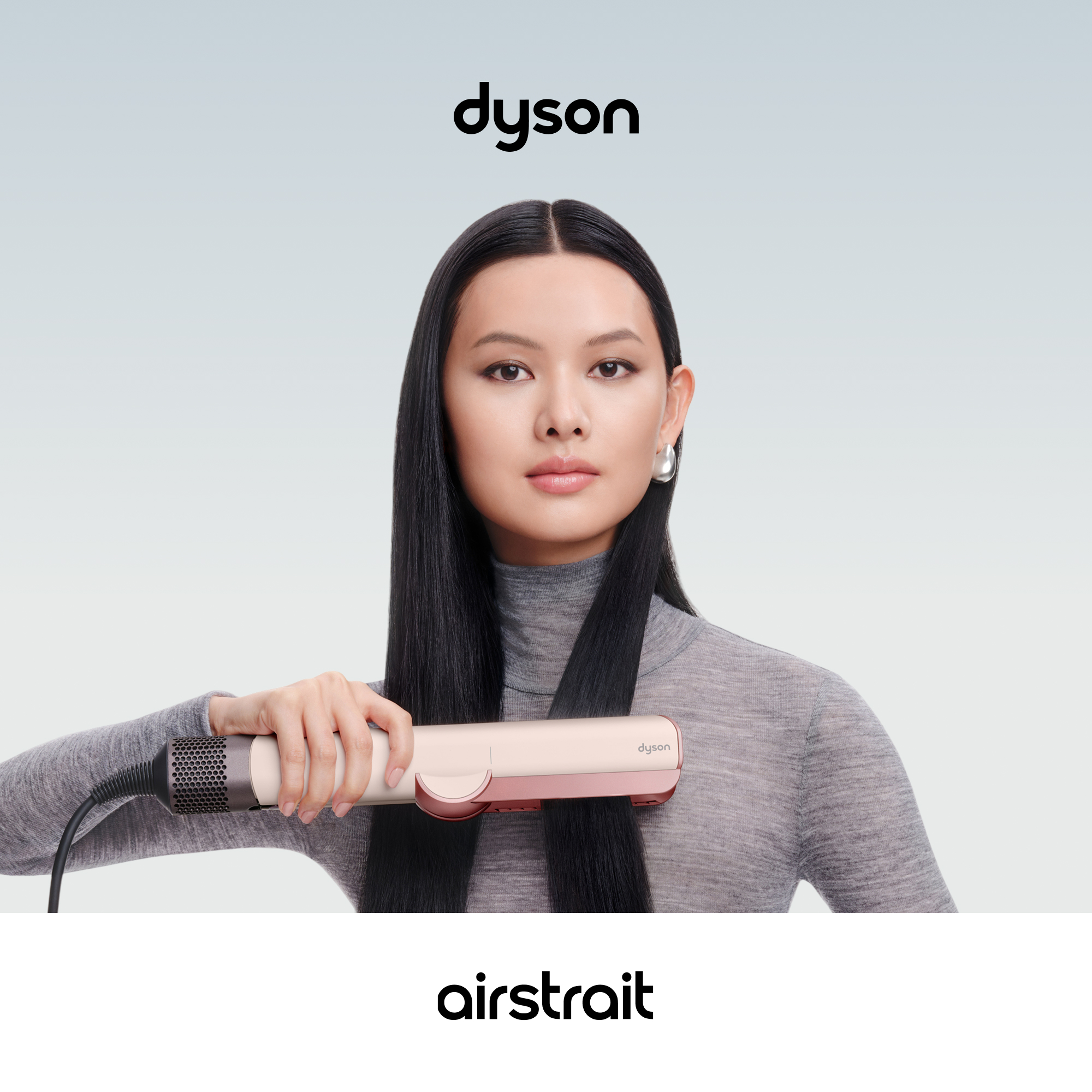 Una mujer sostiene una plancha de pelo Dyson Airstrait alisando su cabello negro y largo ante un fondo claro.