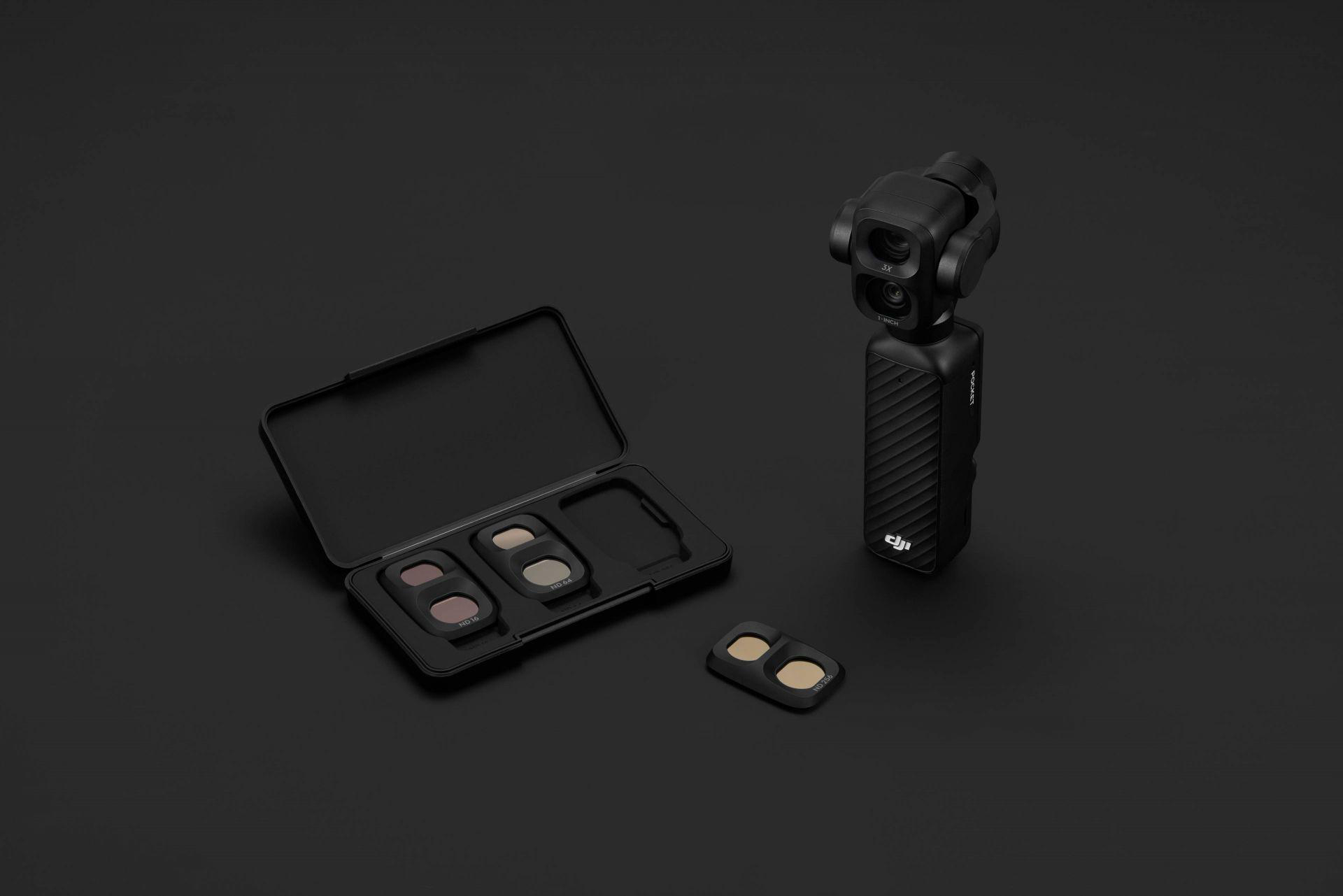 Eine schwarze DJI-Gimbal-Kamera neben einer offenen Zubehörbox mit ND-Filtern auf dunklem Hintergrund.