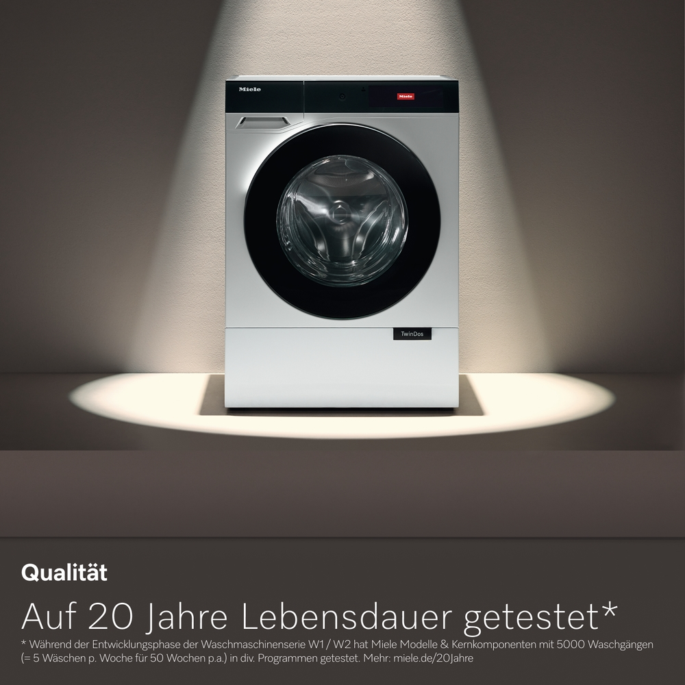Eine weiße Miele Waschmaschine steht im Scheinwerferlicht mit Text unten.