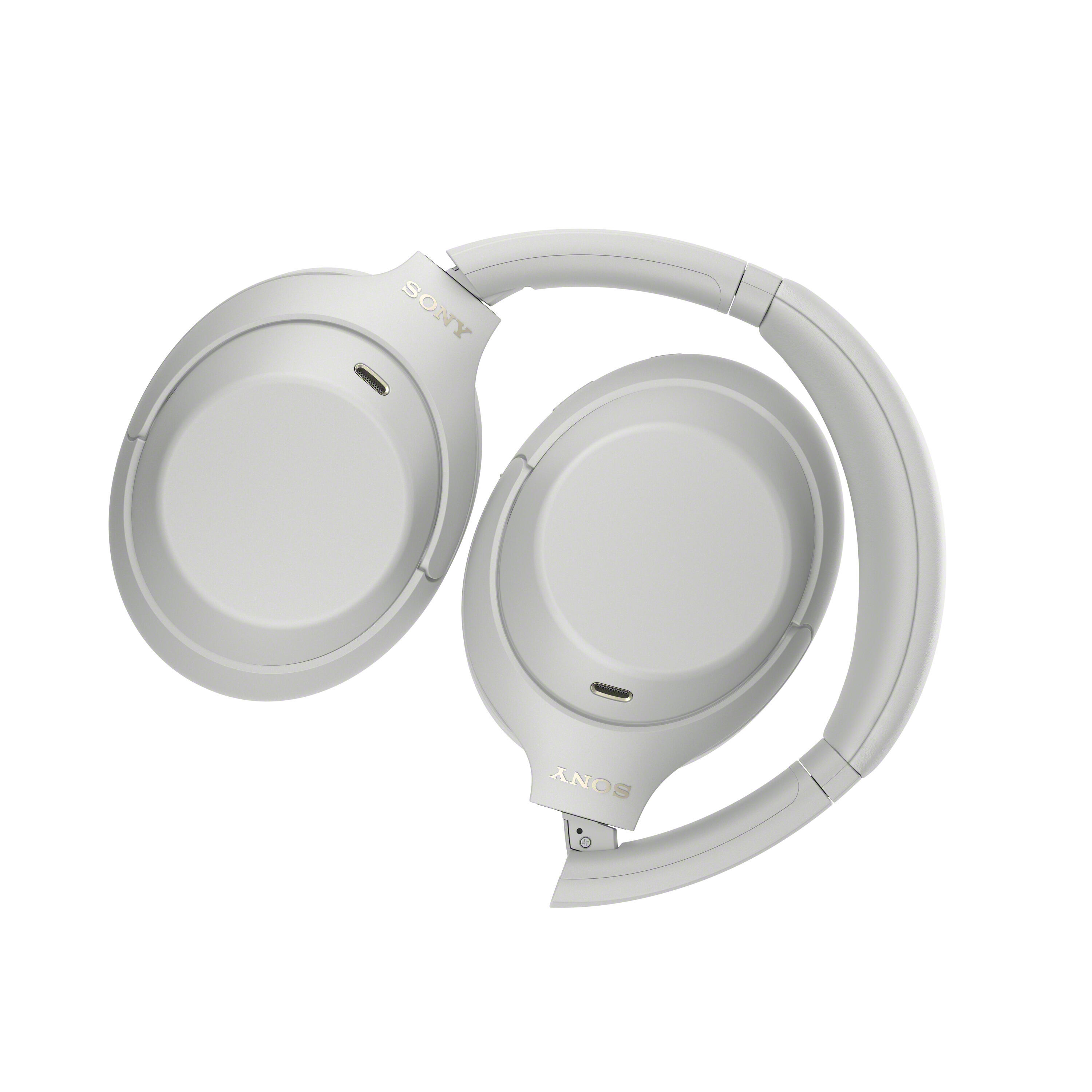 Auriculares inalámbricos Sony blancos plegados con orejeras y diadema visibles sobre fondo blanco.