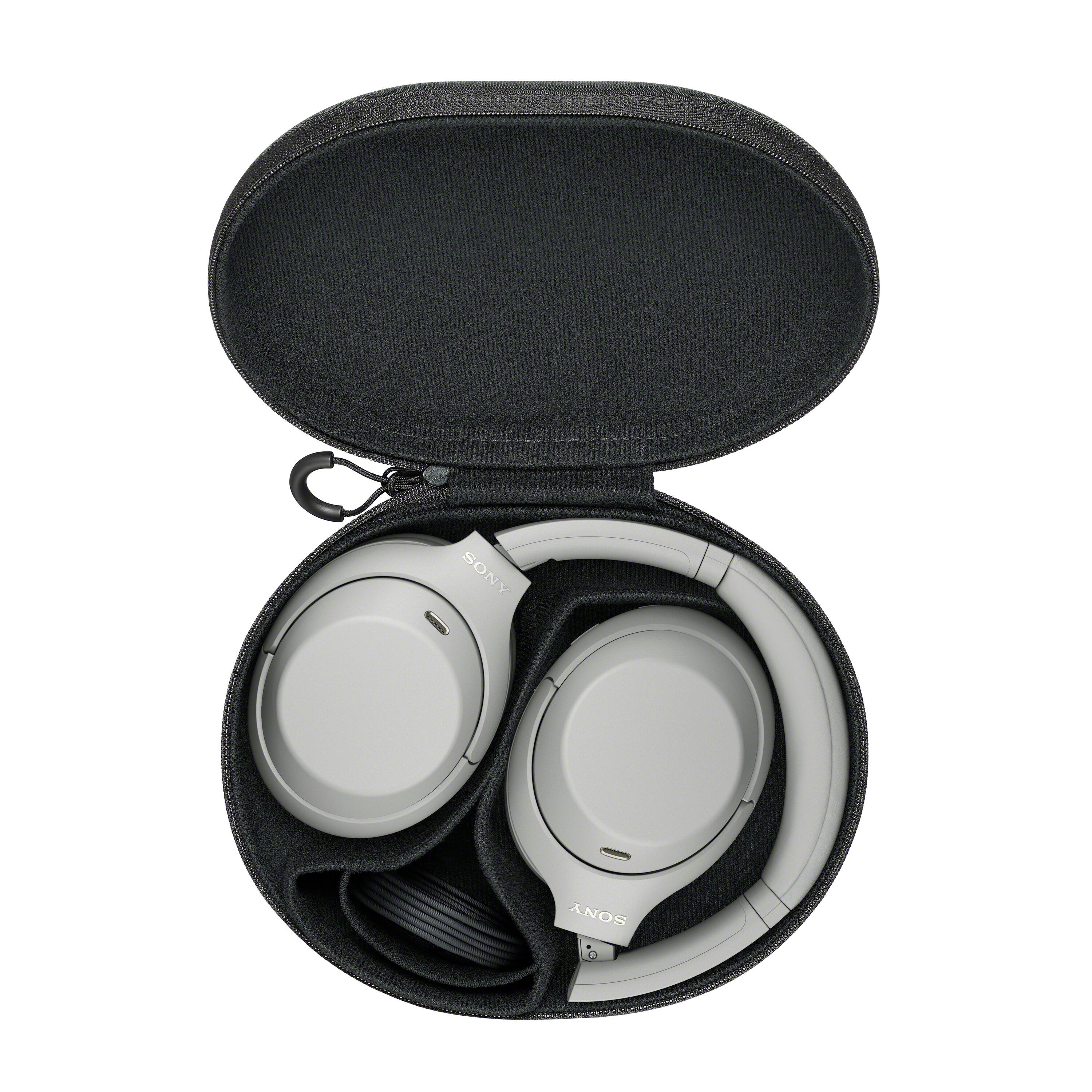 Auriculares grises Sony doblados ordenadamente dentro de un estuche negro redondo y rígido abierto.