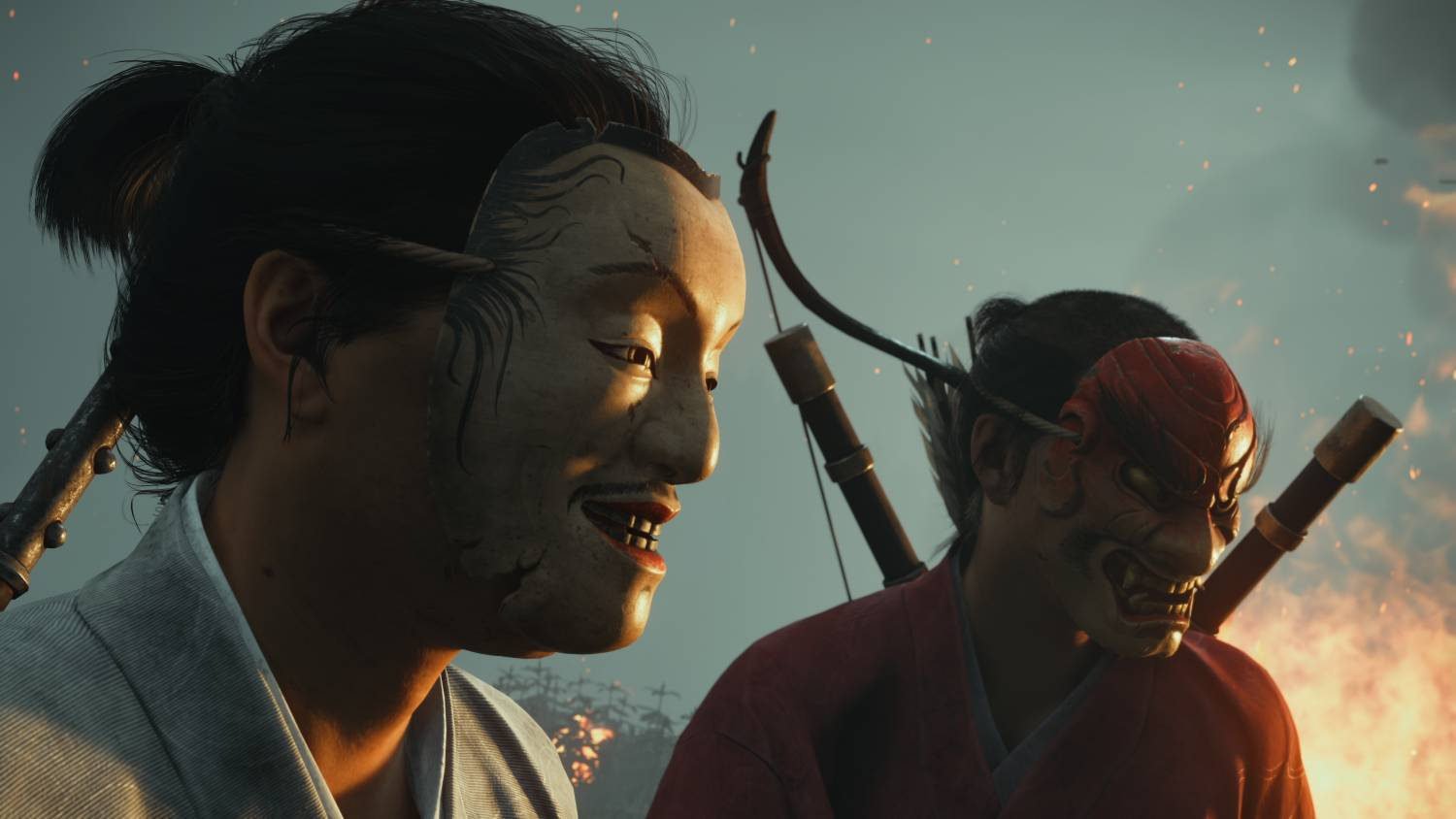 Dos personas con vestimenta tradicional japonesa llevan máscaras frente a un fuego.