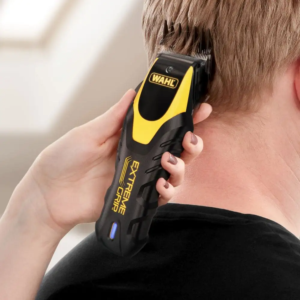 Eine Hand hält eine schwarz-gelbe Wahl Haarschneidemaschine, die Haare am Hinterkopf schneidet.