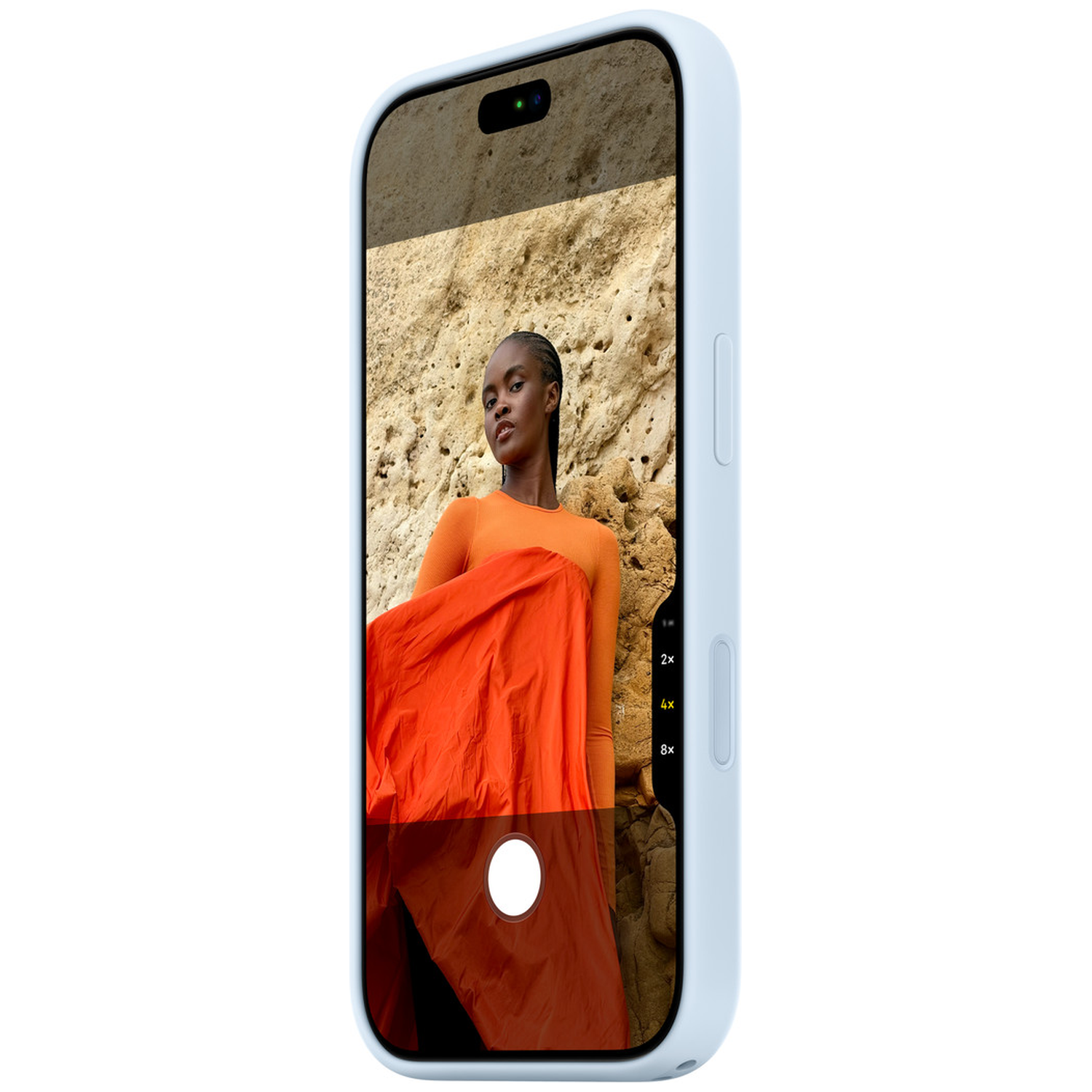 Un smartphone blanc affiche à l'écran une femme en robe orange devant un mur rocheux.