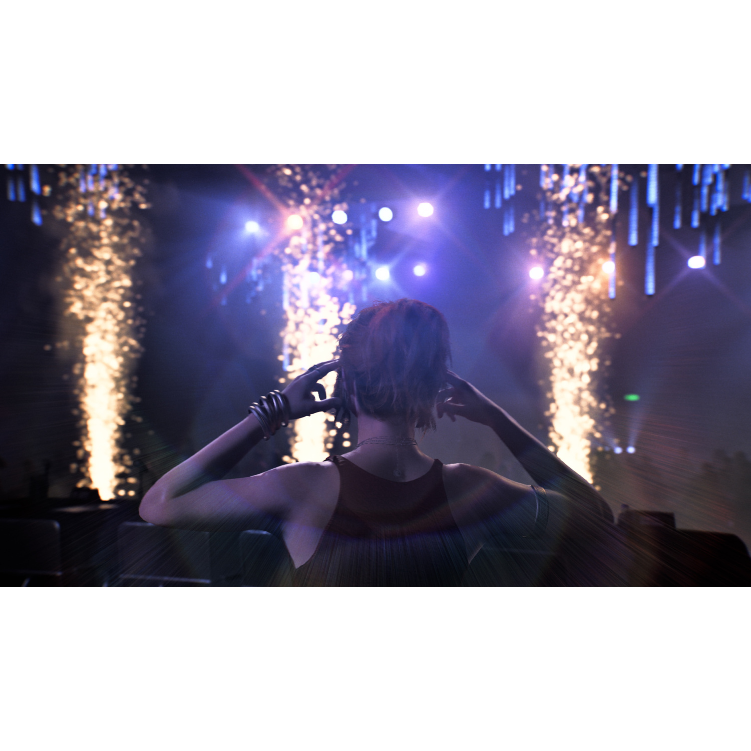 Una persona vista da dietro di fronte a un palco illuminato con fuochi d'artificio e luci blu.