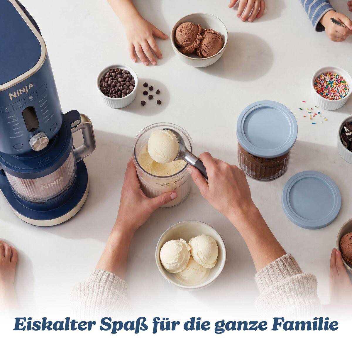Eiskalter Spaß für die ganze Familie mit einer blauen Eismaschine und verschiedenen Toppings auf dem Tisch.