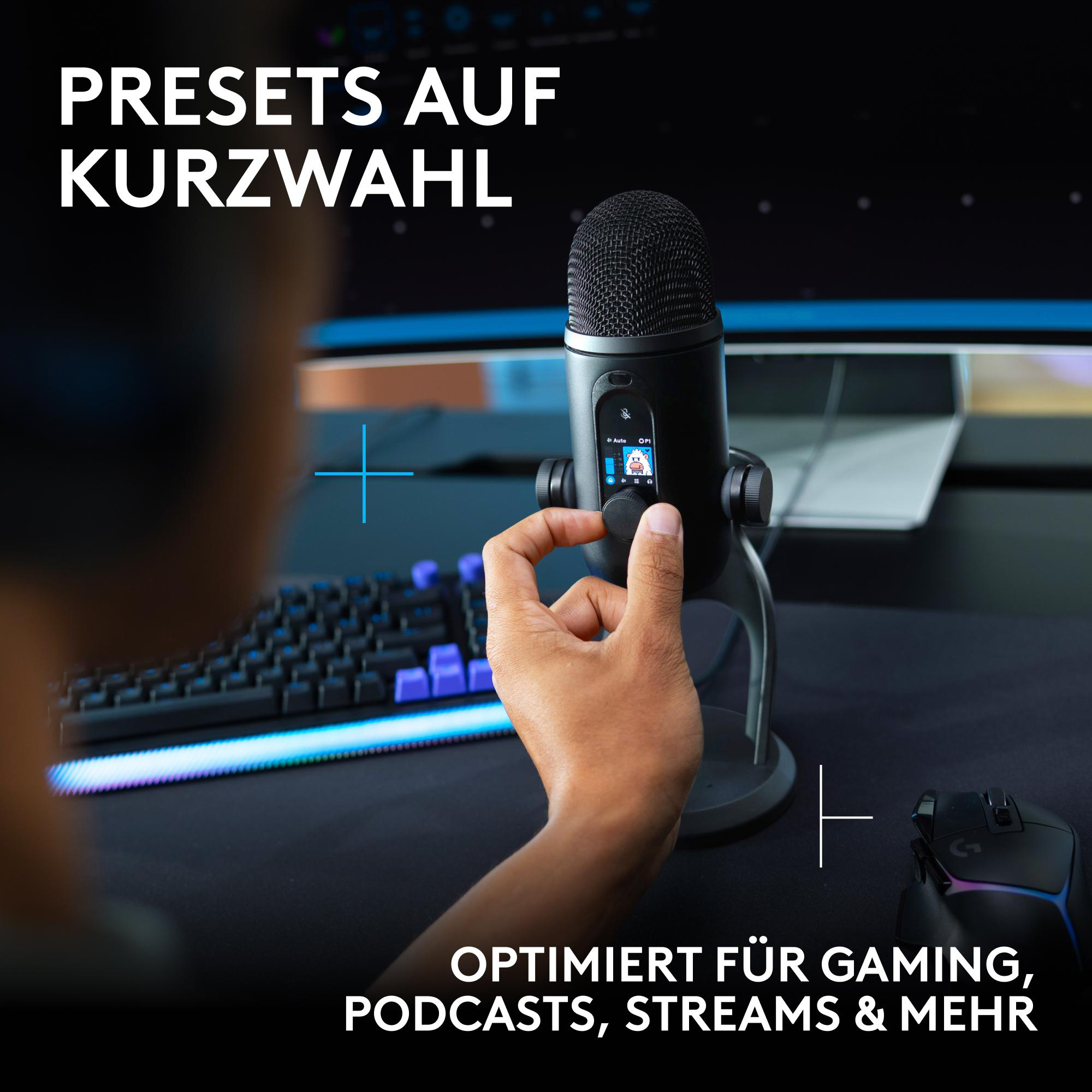 Hand bedient ein schwarzes Mikrofon vor einer Tastatur und einem Monitor.