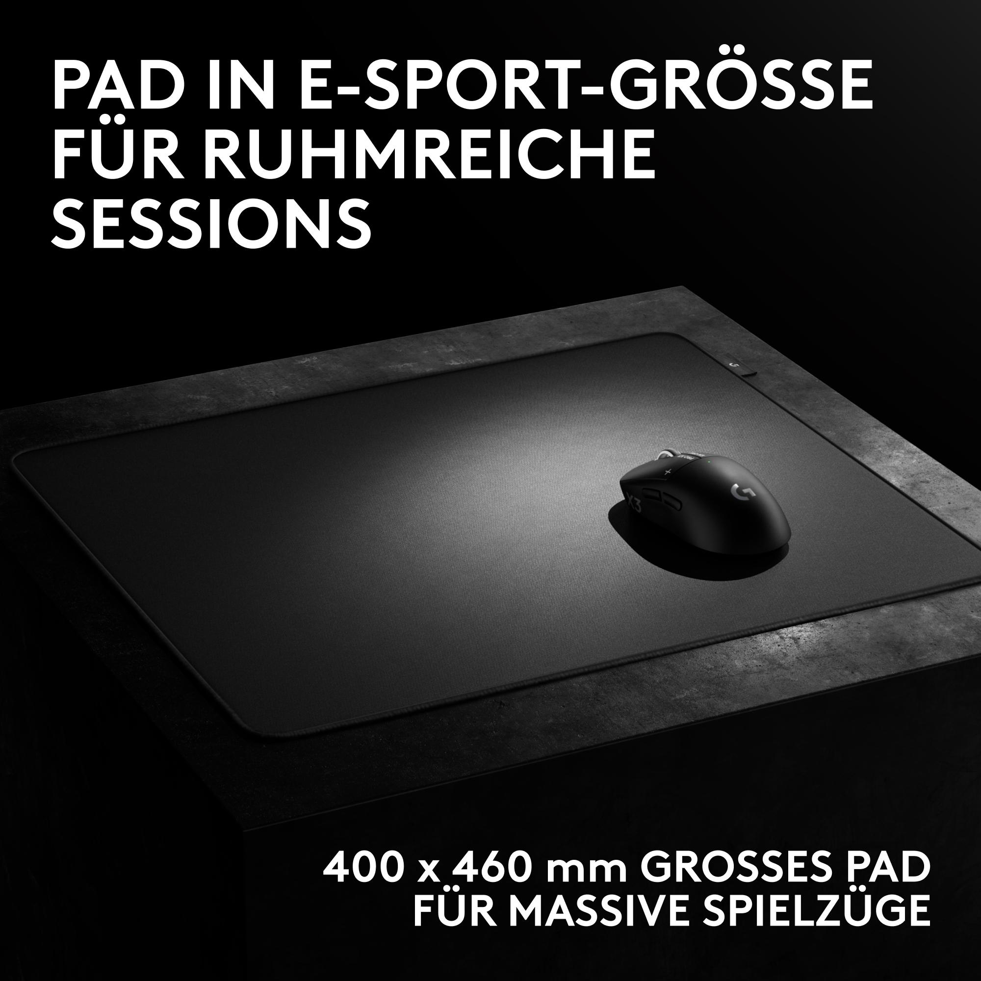 Schwarze Gaming-Maus auf großem schwarzen Mauspad auf dunklem Tisch.