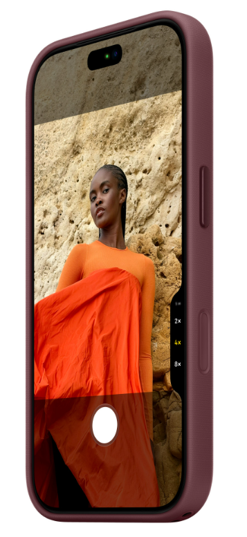 Fioletowy smartfon wyświetla zdjęcie kobiety w odcieniach pomarańczy na tle skalnej ściany.