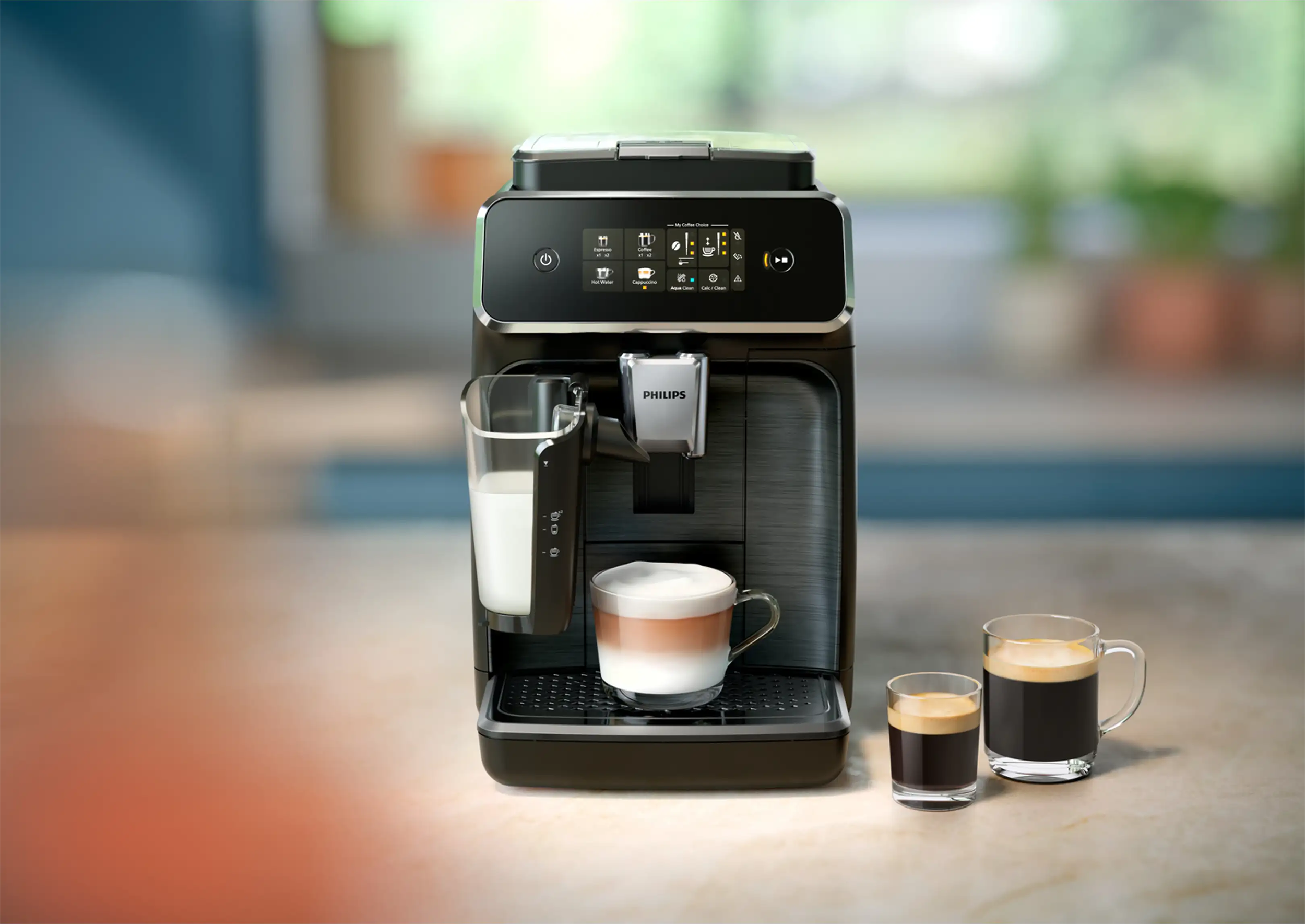Egy fekete Philips kávéfőző pulton, mellette egy latte macchiato és két eszpresszós csésze.