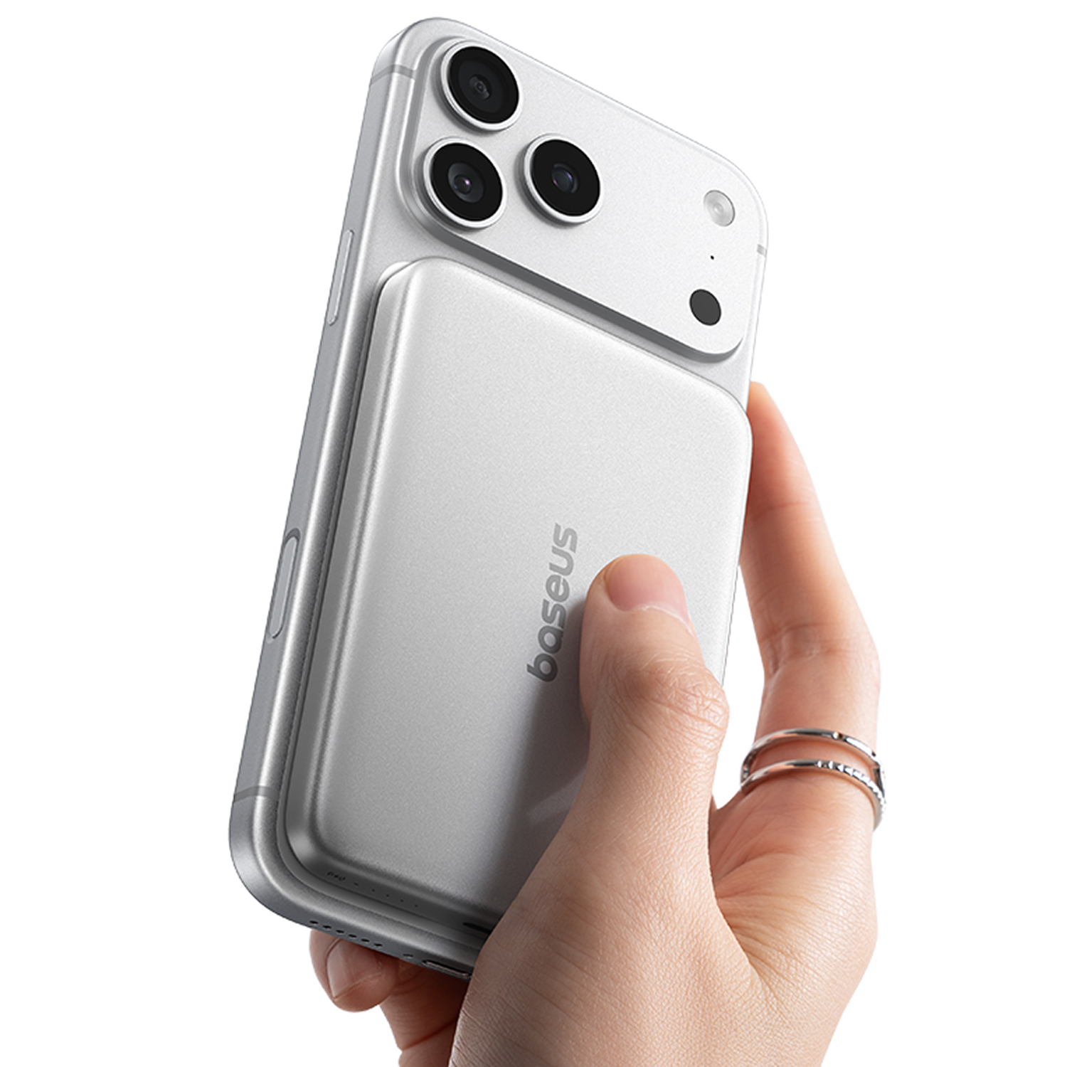 Una mano sostiene un smartphone plateado con una batería externa magnética en la parte trasera.