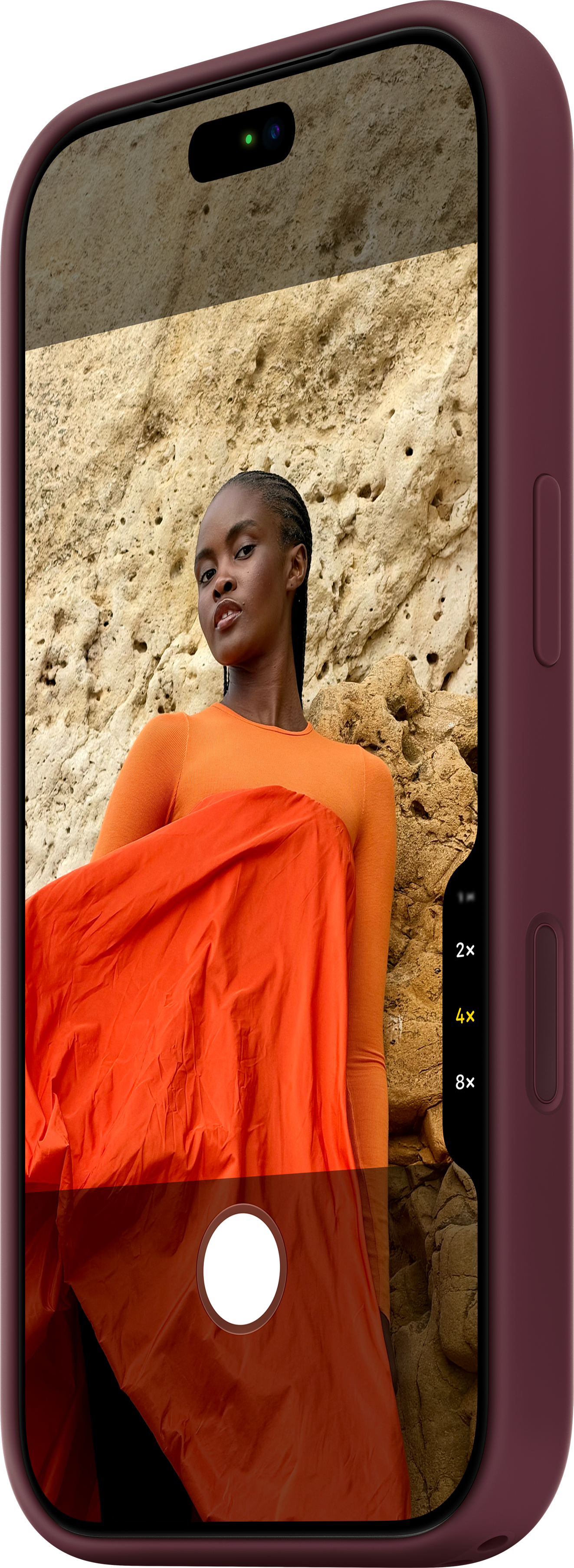 Un smartphone affiche sur son écran une femme en vêtements orange devant un mur de grès.