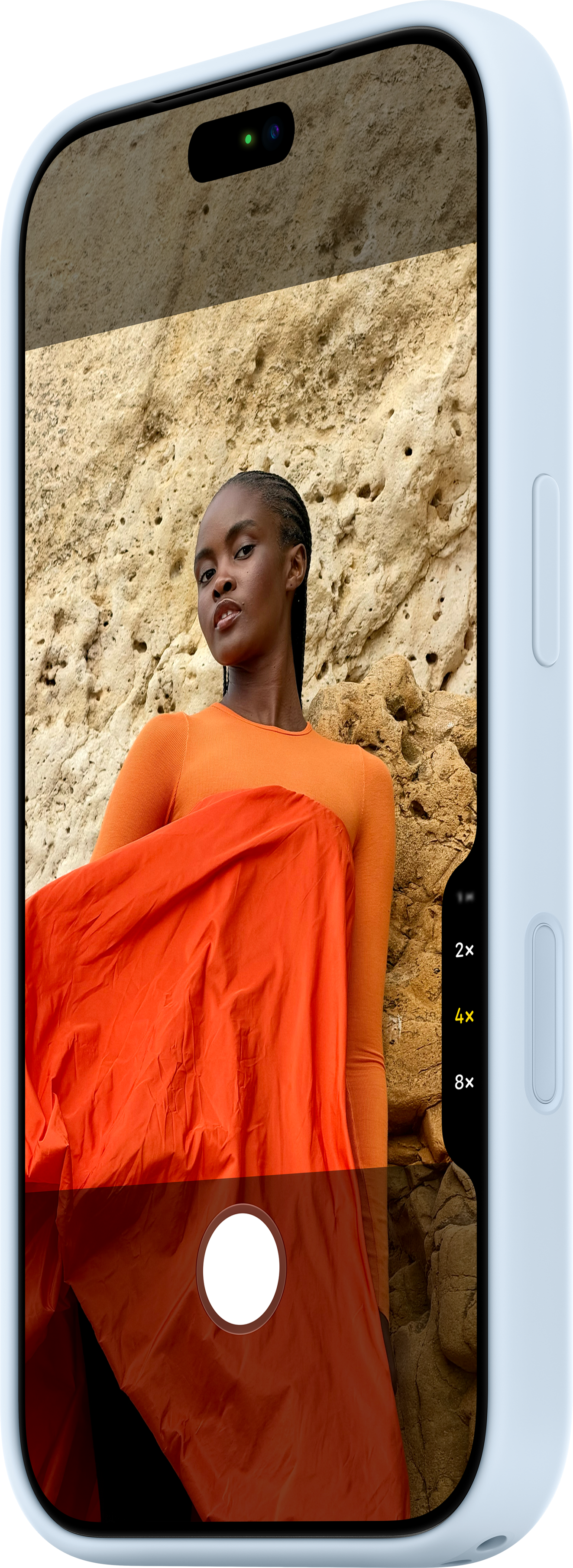 Un écran de smartphone affiche une femme en haut orange devant un mur rocheux.