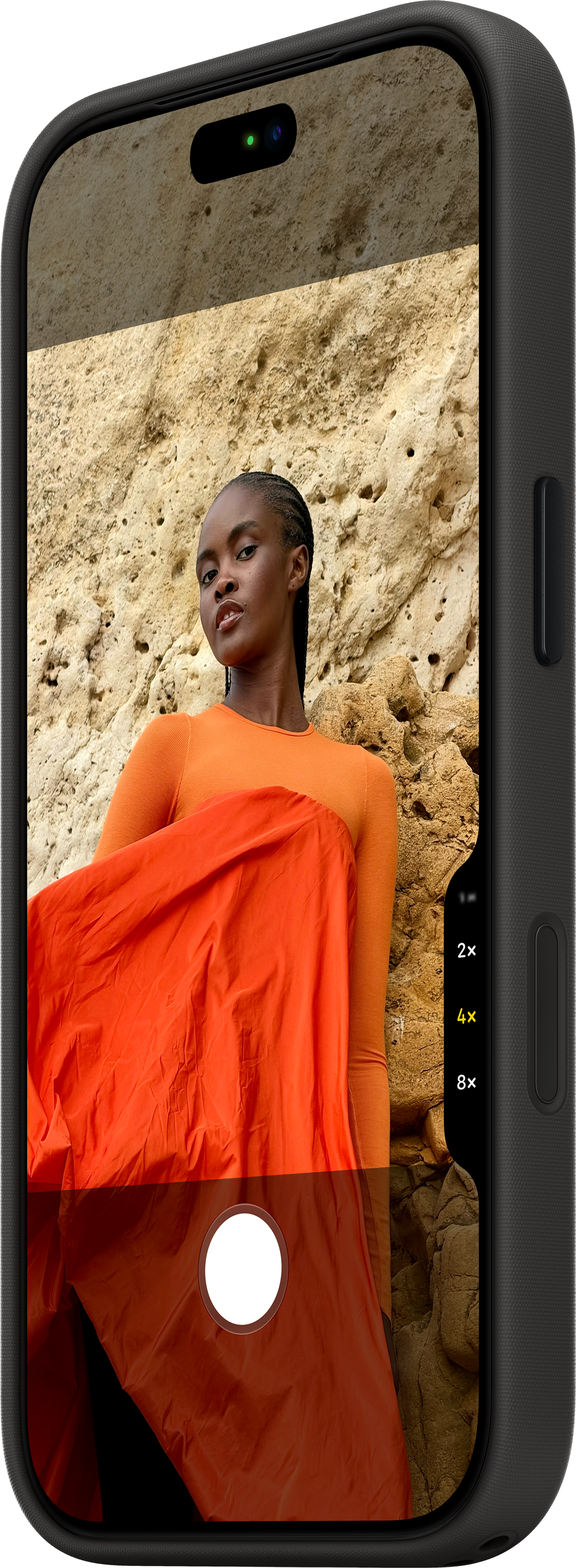 Écran de smartphone affichant une femme en orange devant un mur de roche, avec des boutons de zoom.
