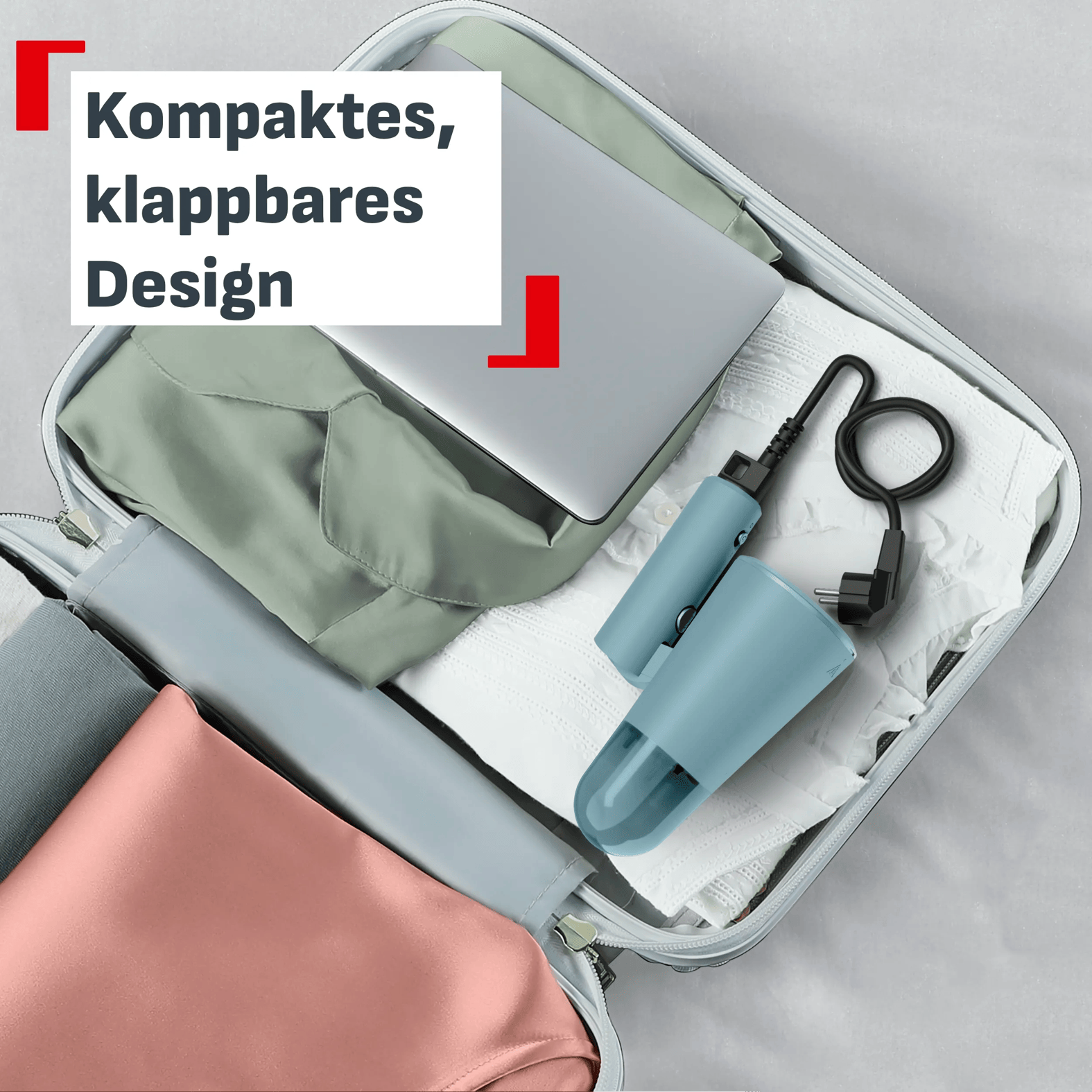 Ein offener Koffer mit gefalteter Kleidung, einem Laptop und einem blauen Reisebügeleisen.