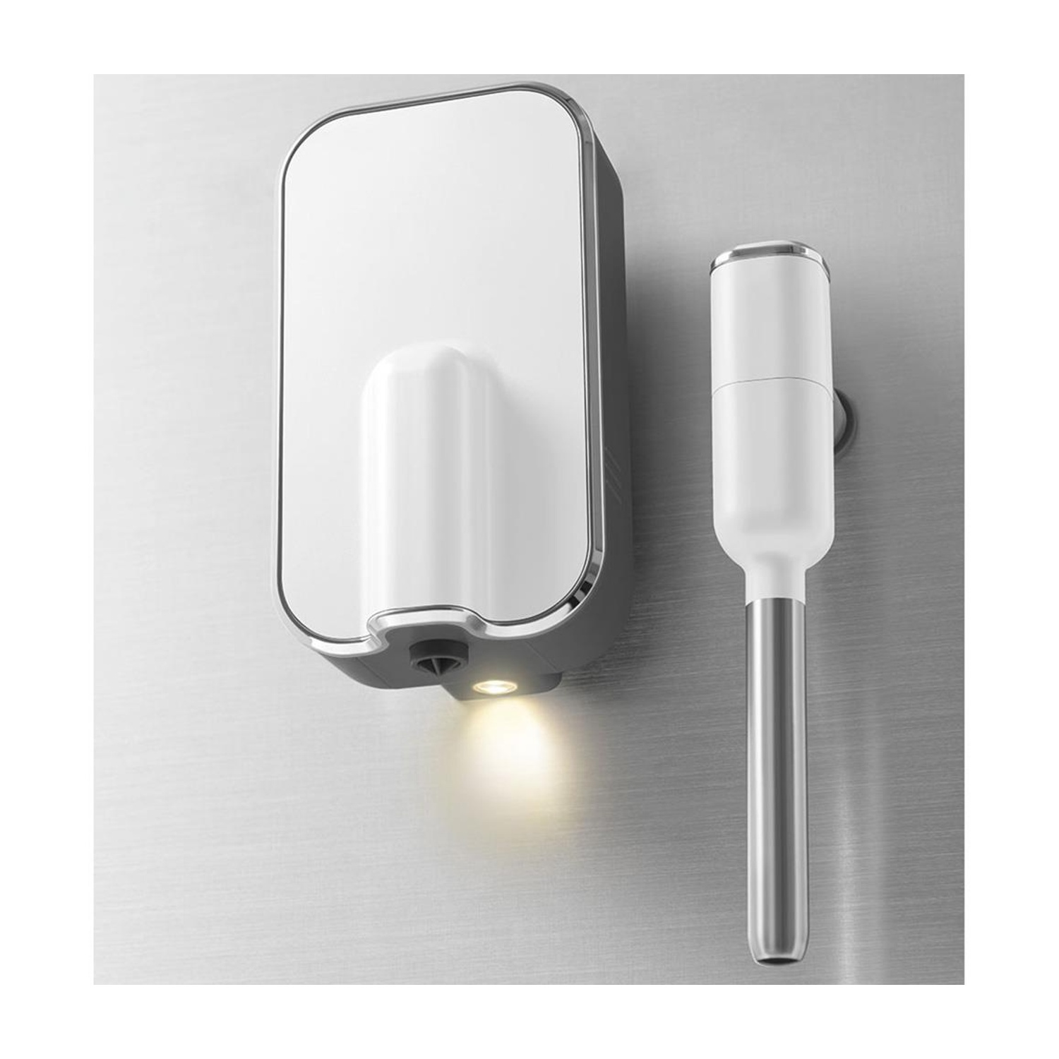 Distributore di sapone bianco a parete con fondo illuminato e dispositivo a bacchetta accanto.