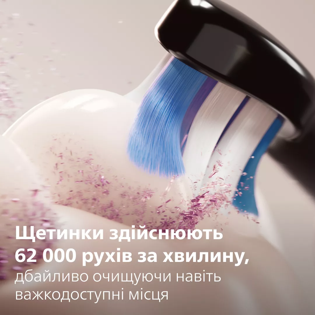 Zahnbürstenkopf mit blauen und weißen Borsten reinigt Zahncreme mit rosa Partikeln.