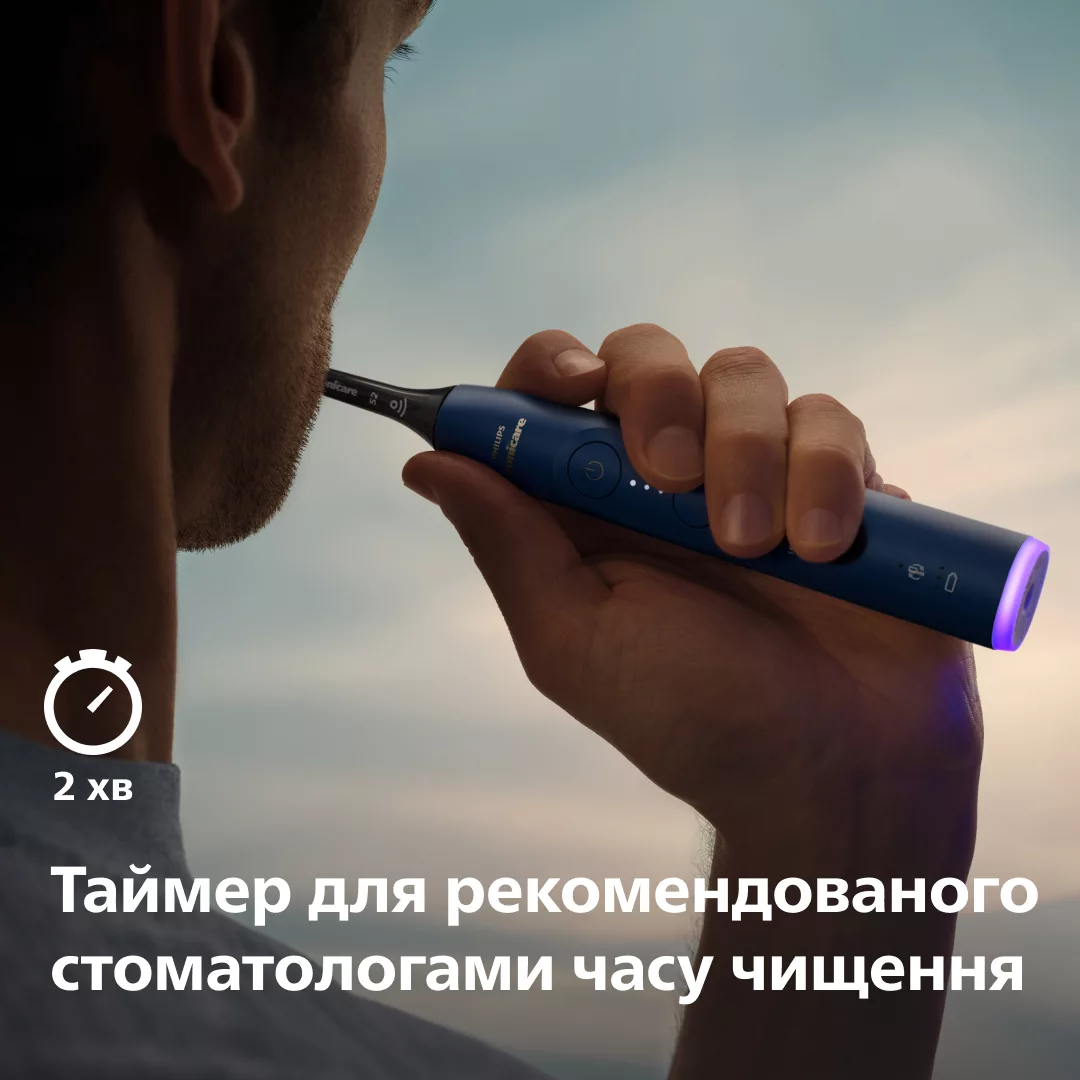 Ein Mann putzt sich die Zähne mit einer blauen Philips Sonicare Zahnbürste gegen einen bewölkten Himmel.