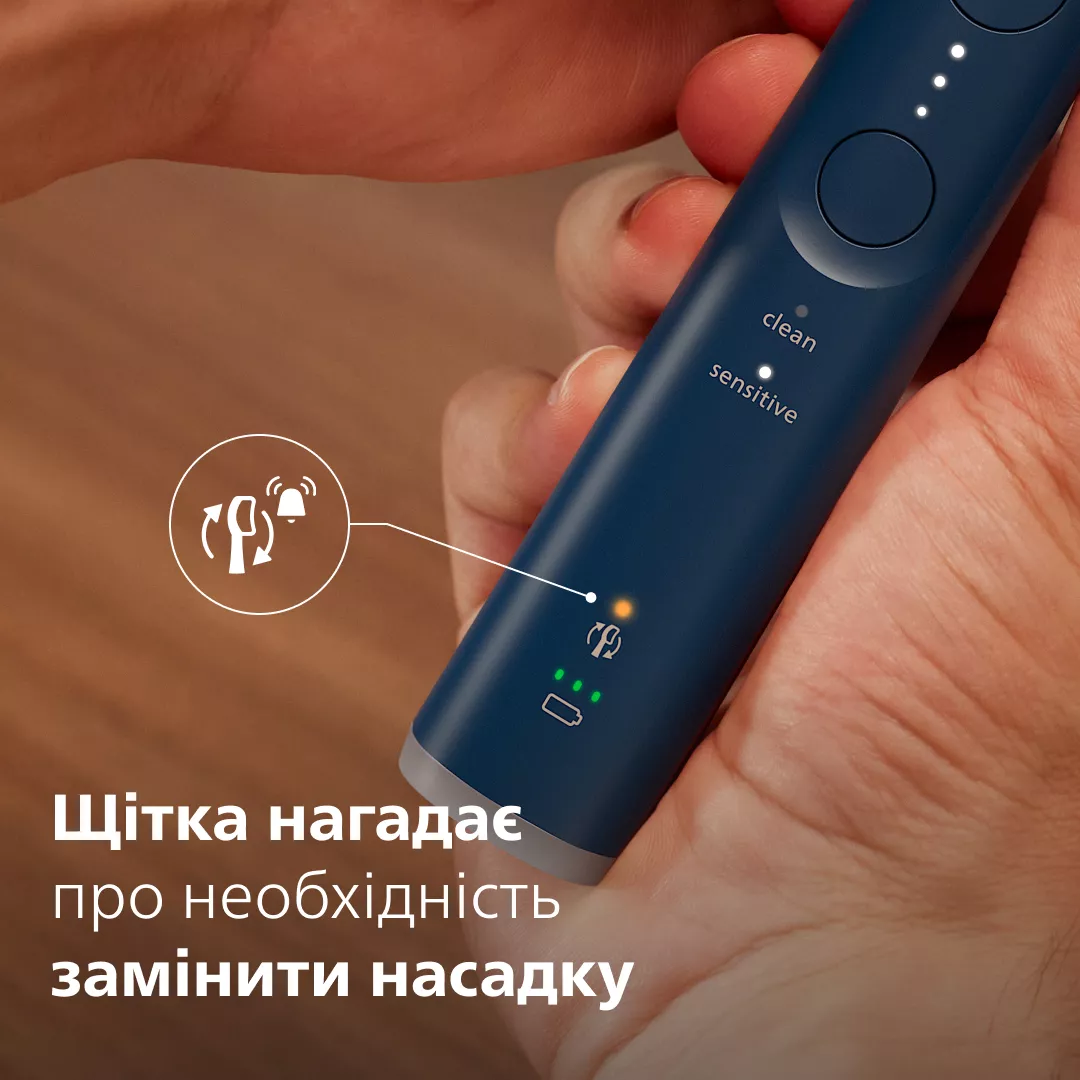 Eine Hand hält eine blaue elektrische Zahnbürste mit einer orangen LED für den Bürstenkopfwechsel.