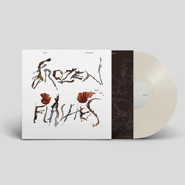 Eine weiße Vinyl-Schallplatte mit Hülle zeigt den Text 'Frozen Flashes' in braunen und schwarzen Pinseltönen.