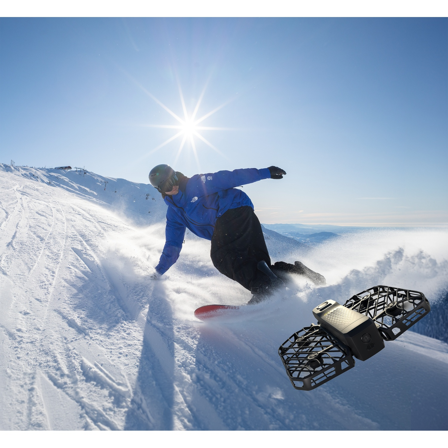 Uno snowboarder scende lungo un pendine soleggiato mentre un drone vola vicino.