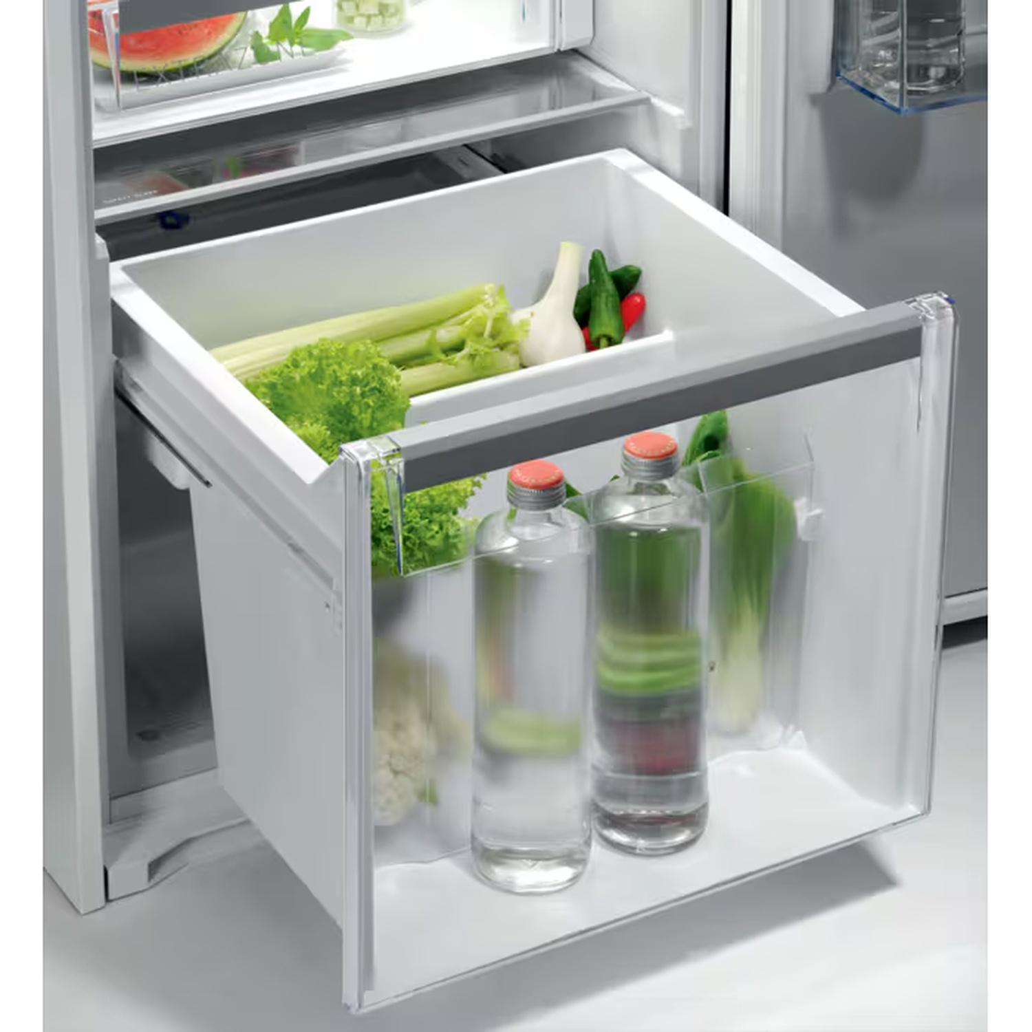 An open refrigerator drawer contains two water bottles, celery, lettuce, and peppers.