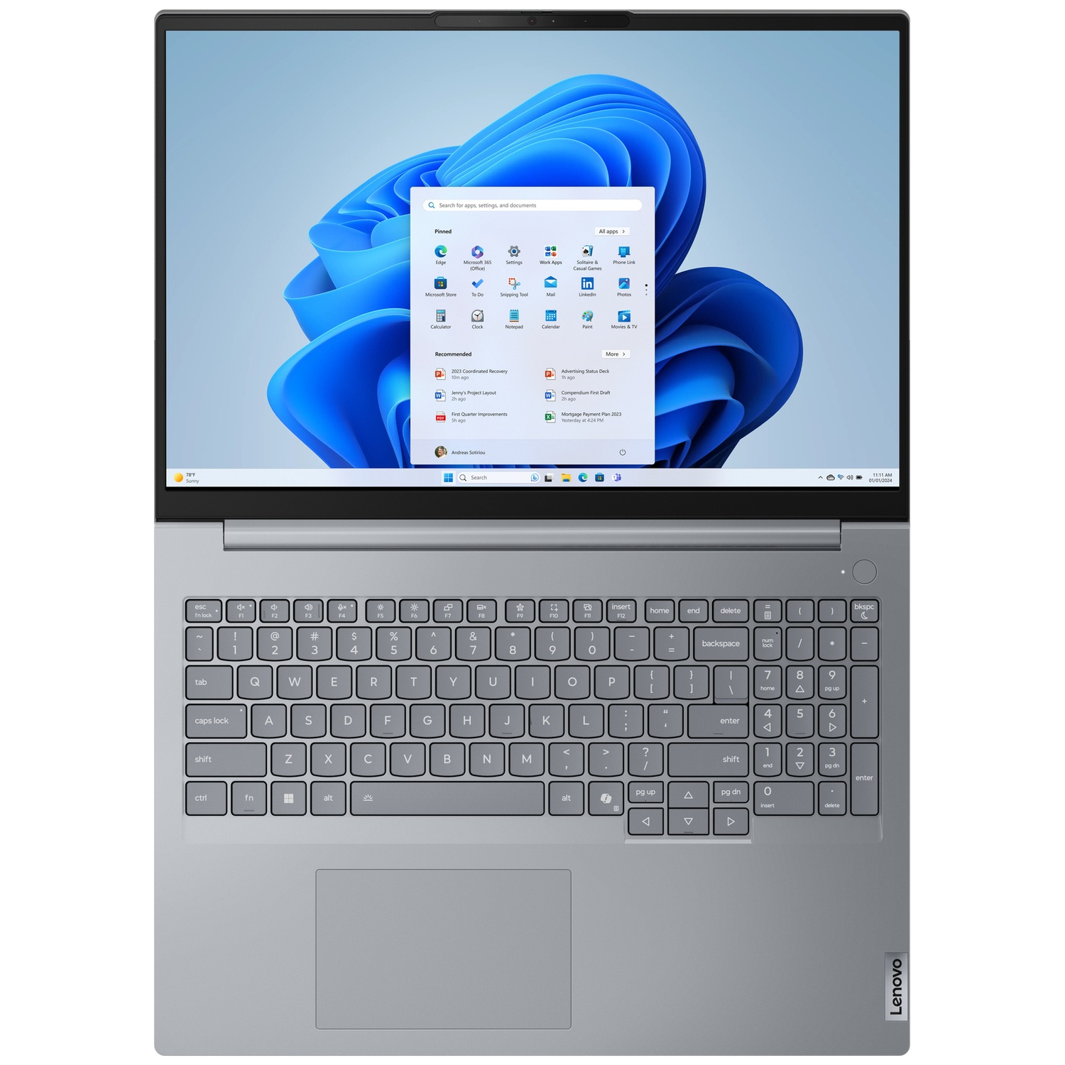 Bovenaanzicht van een open grijze laptop met het Windows-startmenu op het blauwe scherm.