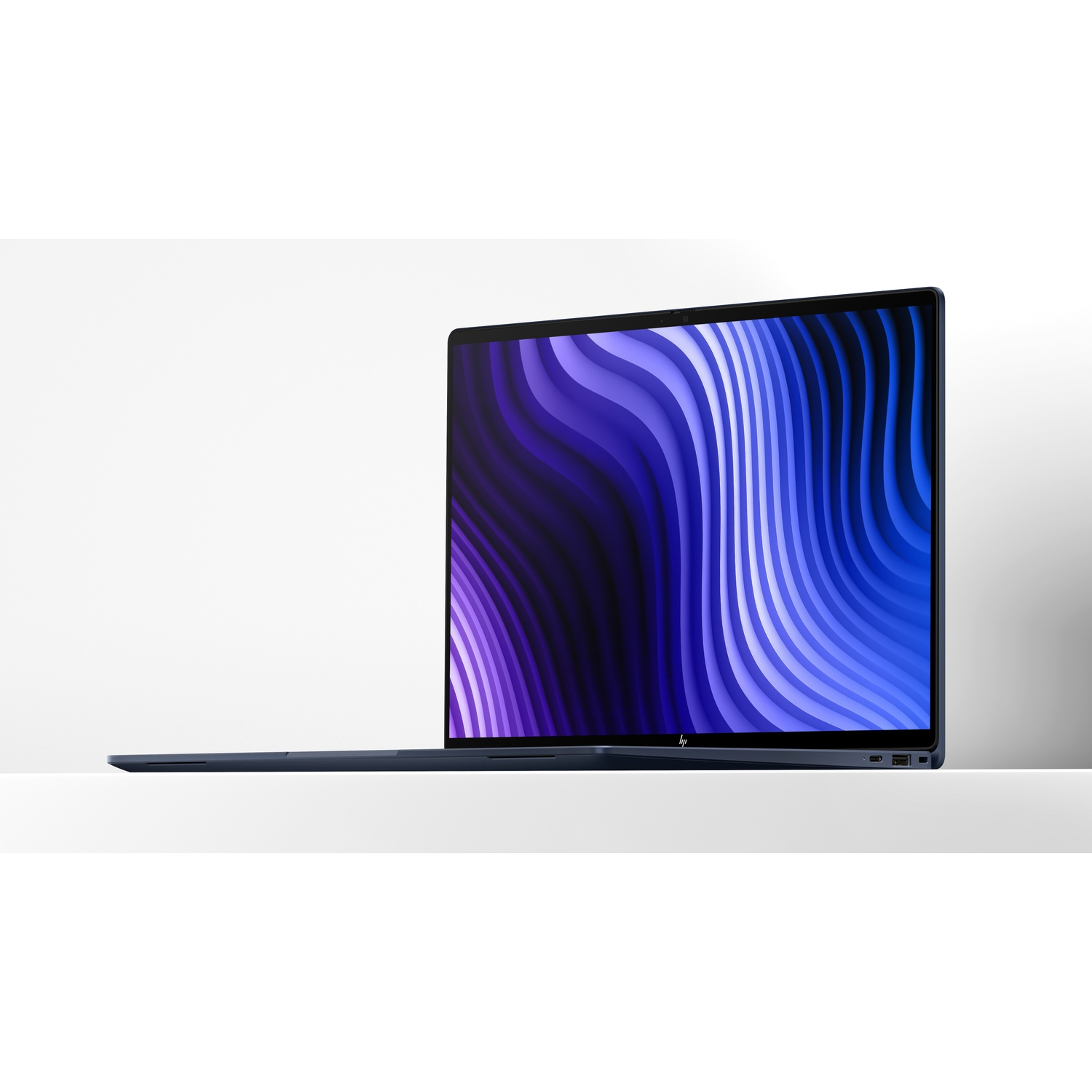 Een donkerblauwe laptop op een wit oppervlak met een paars-blauwe abstracte golven wallpaper.