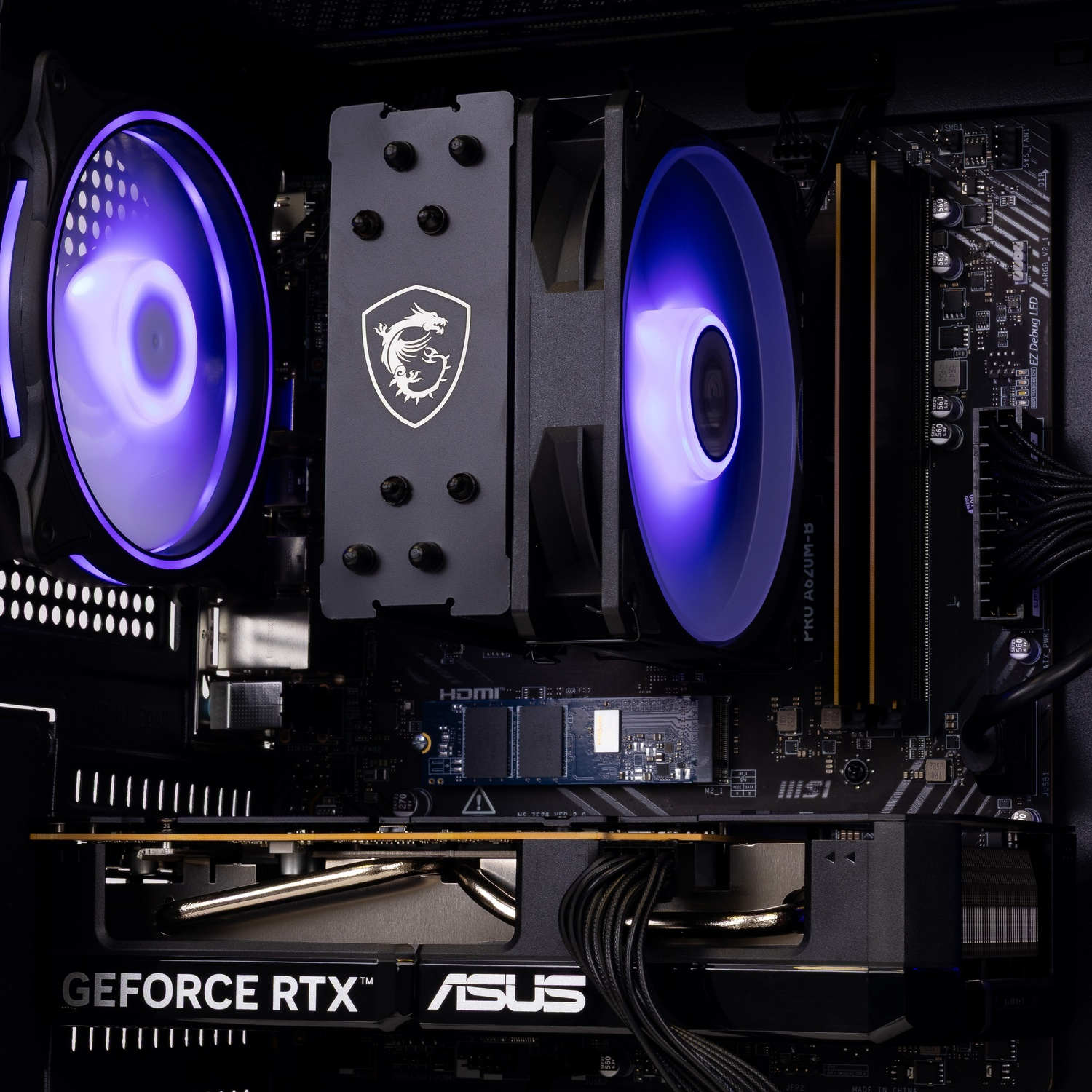 PC interior with MSI CPU cooler, blue glowing fans, and ASUS GeForce RTX graphics card on a motherboard.