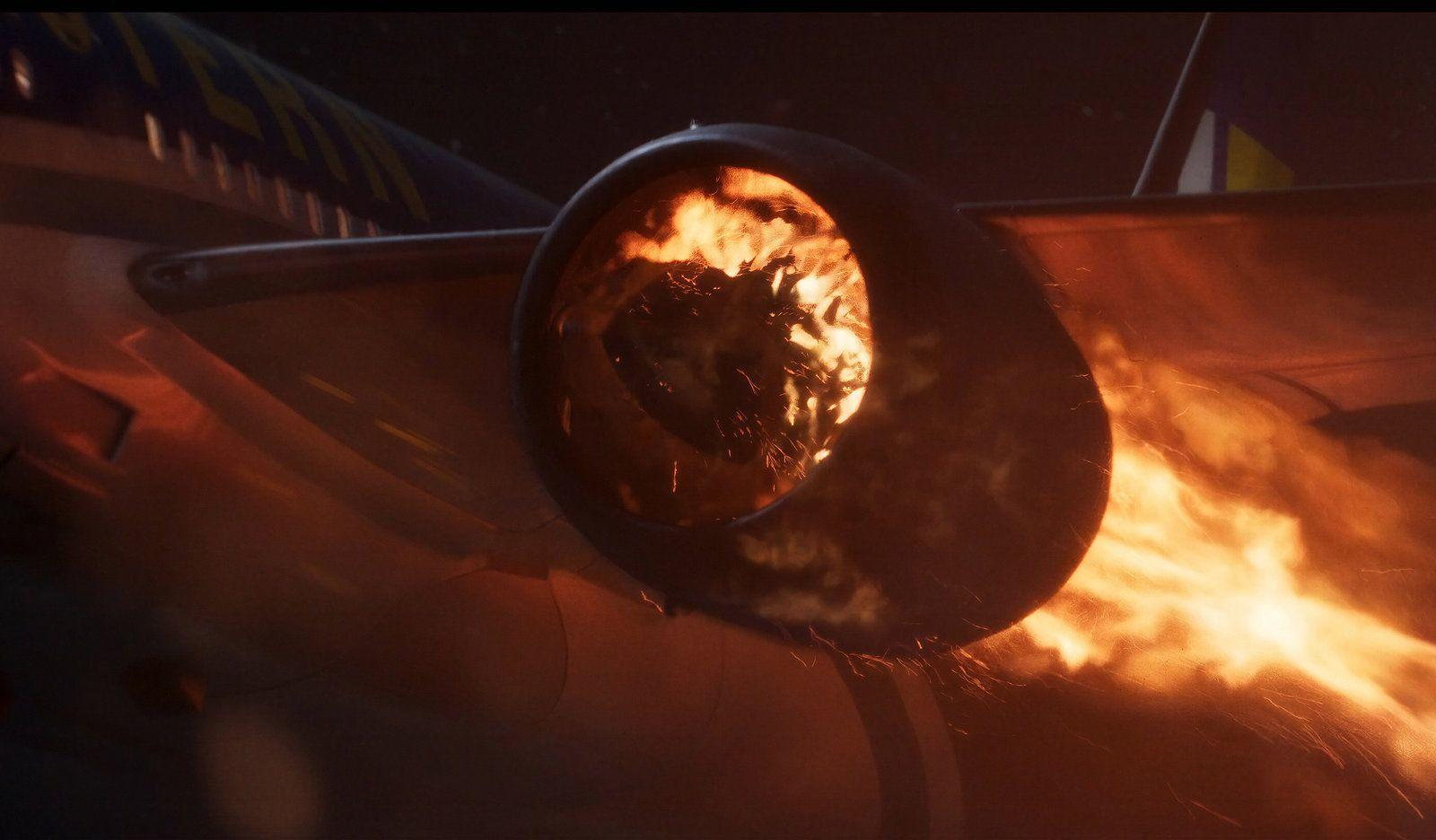 Ein Flugzeugturbinentriebwerk brennt und speit helle orangefarbene Flammen und Funken vor dunklem Hintergrund.