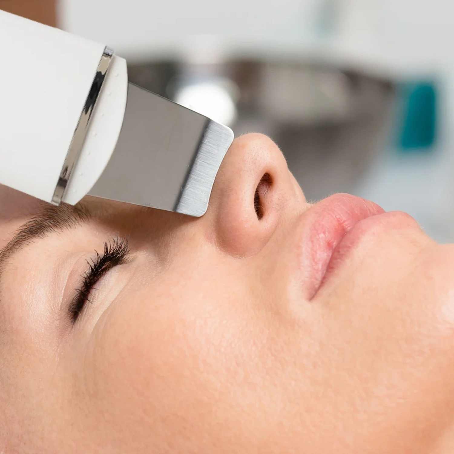 Una donna che riceve un trattamento viso con una spatola ad ultrasuoni sul naso.