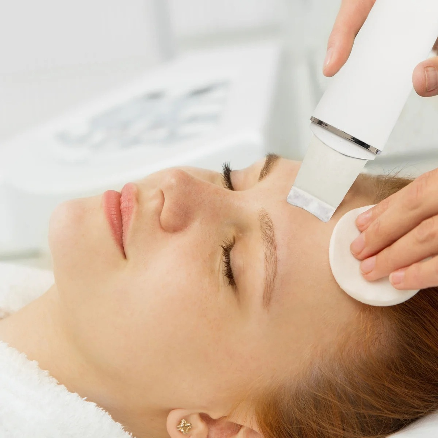 Una donna riceve un trattamento viso utilizzando un dispositivo per la pulizia della pelle sulla fronte.