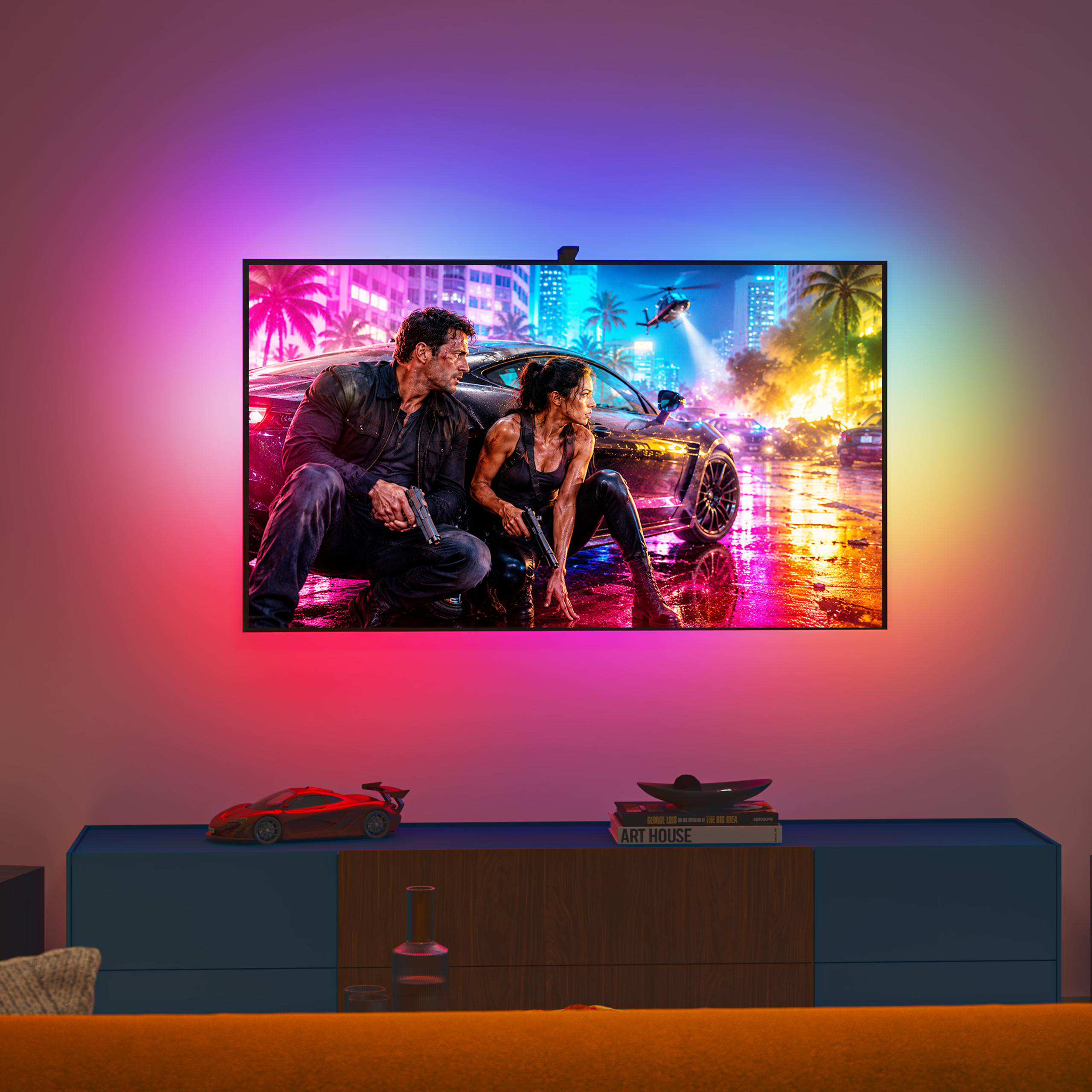 Ein Fernseher zeigt eine Actionszene mit farbiger Hintergrundbeleuchtung an der Wand über einem blauen und hölzernen Lowboard.