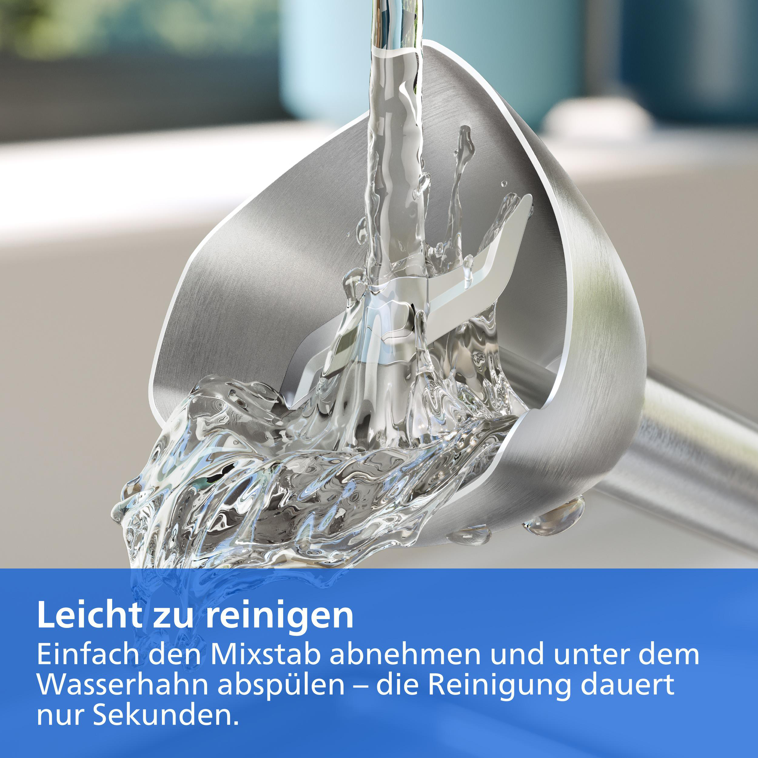 Wasser spült einen Edelstahl-Mixstabfuß mit Messern ab, mit deutschem Text unten.