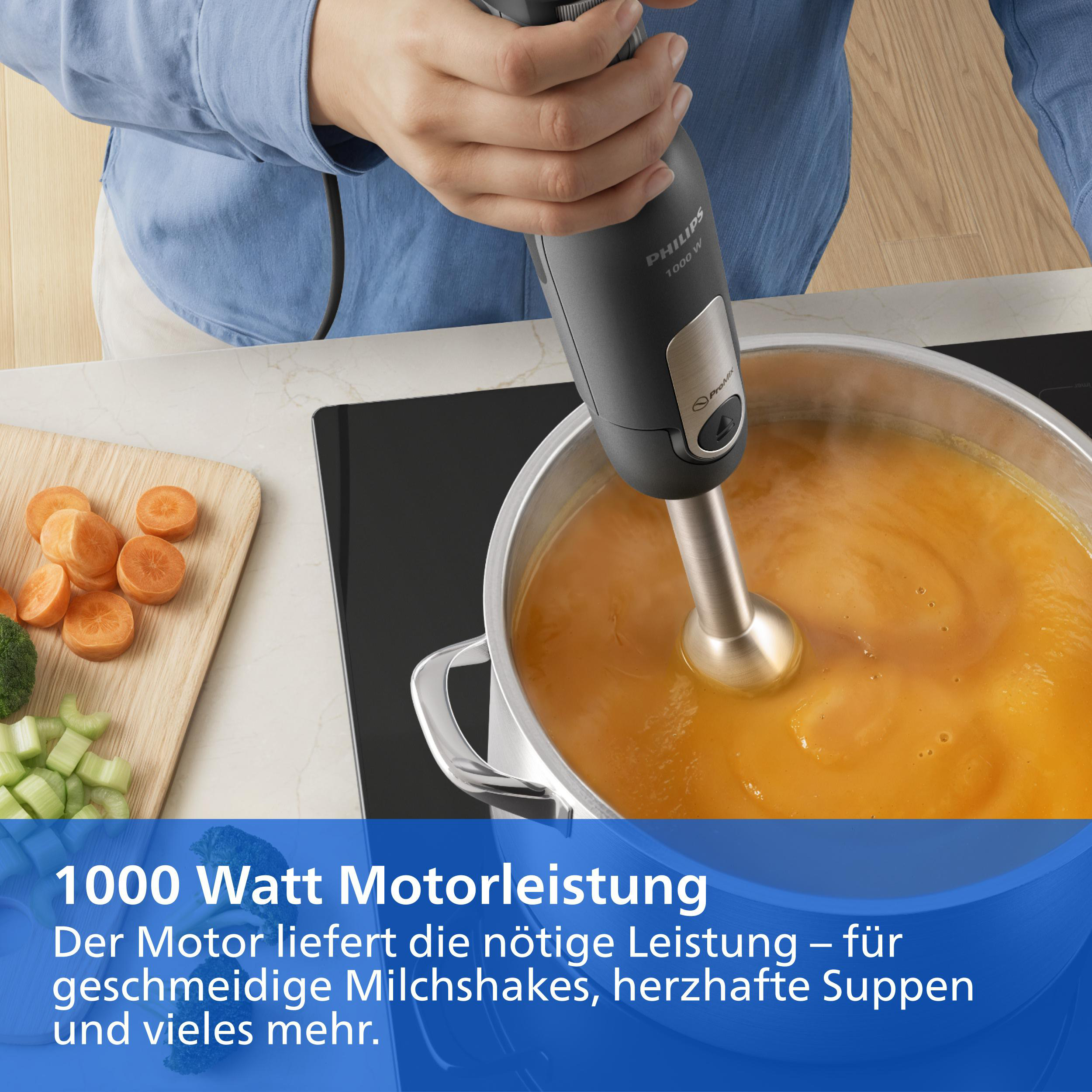 Eine Person nutzt einen Philips Stabmixer, um eine Suppe in einem Topf zu pürieren. Rechts liegen geschnittene Karotten.