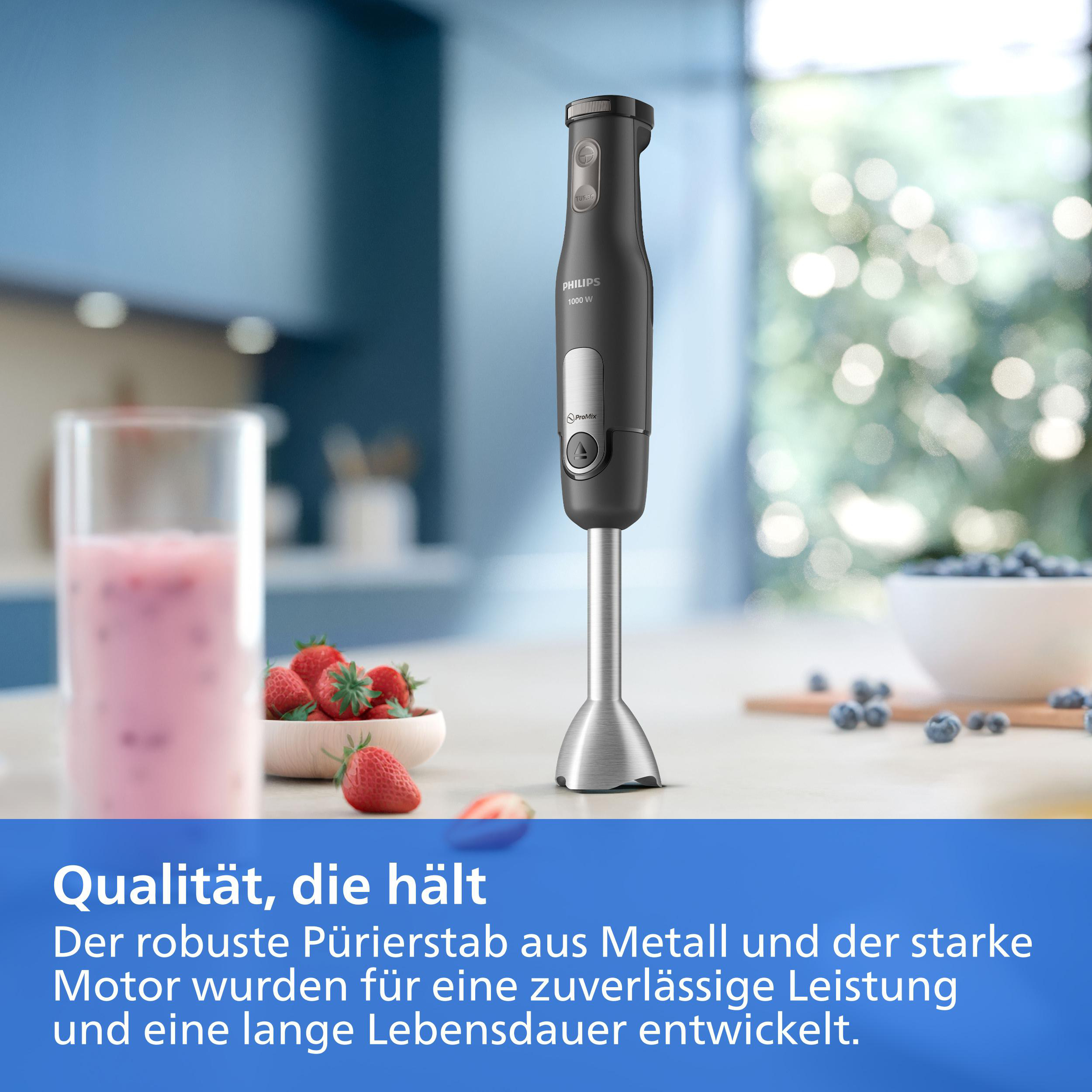 Ein schwarzer Philips Stabmixer steht auf einer Küchentheke mit Erdbeeren und einem rosa Smoothie.
