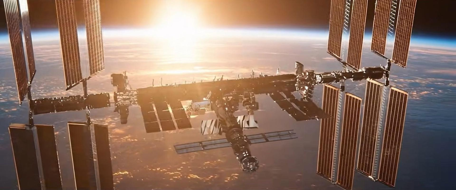 Die Internationale Raumstation umkreist die Erde mit Solarpanelen, die im hellen Sonnenaufgang und am blauen Horizont leuchten.