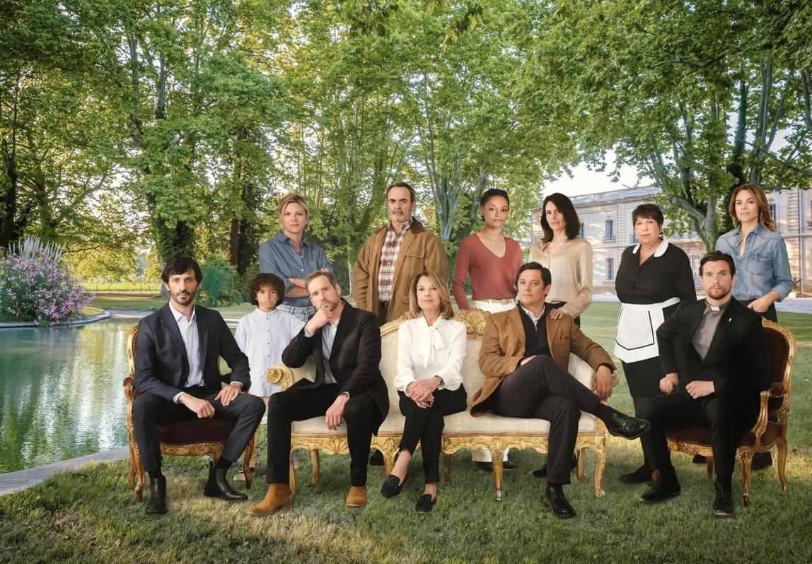 Eine diverse Gruppe von Menschen posiert auf einem Sofa und stehend im Garten vor einem Gebäude und Bäumen.