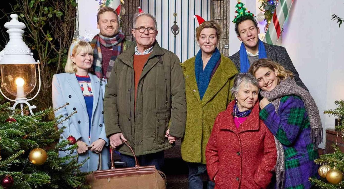 Eine mehrgenerationale Familie steht zusammen im Freien mit Weihnachtsdekorationen im Hintergrund.