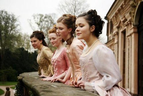 Vier Frauen in historischen Kleidern stehen auf einem Balkon und blicken nach vorn.